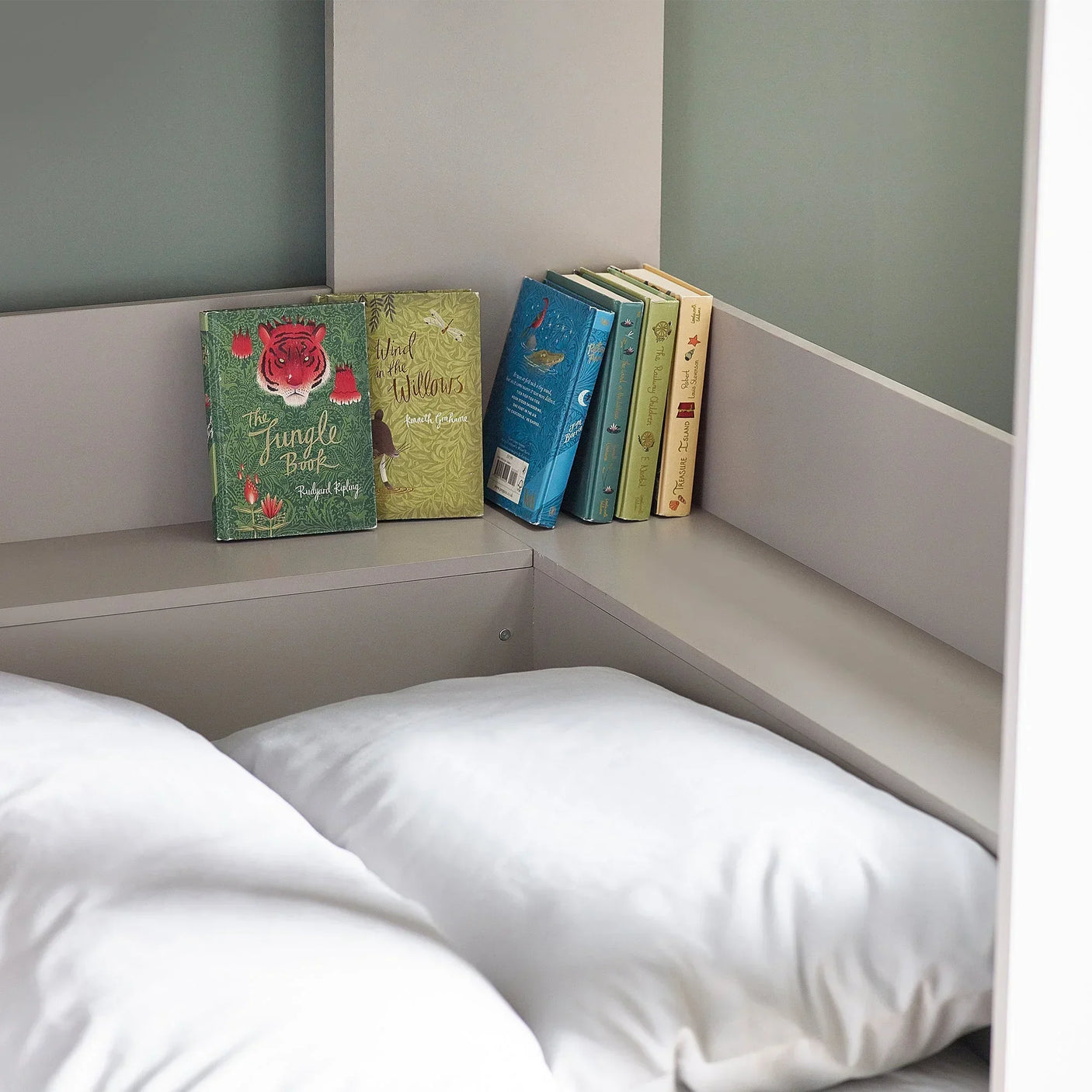 Taupe bunk bed corner shelf with books and white bedding