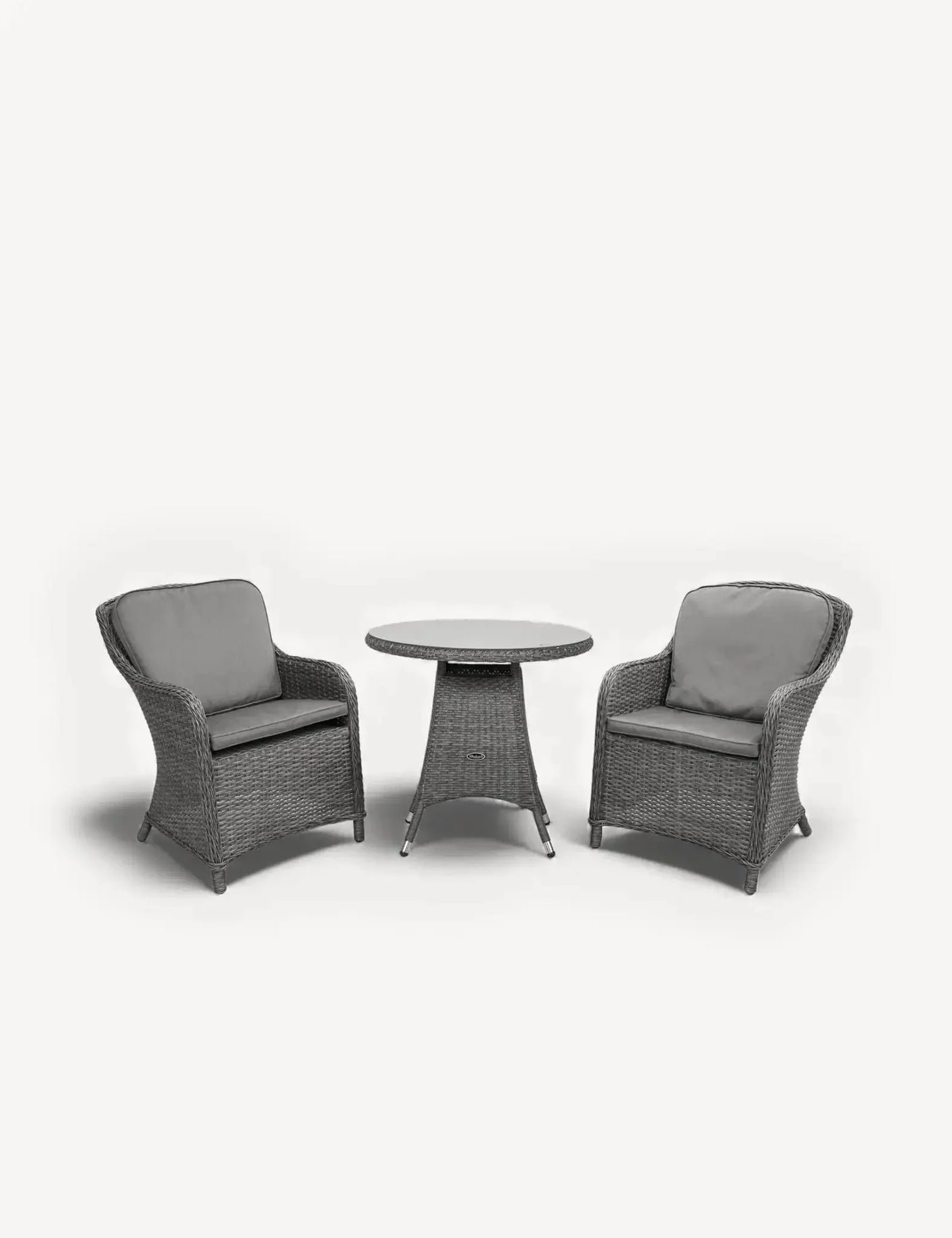 Grey rattan bistro set with two cushioned armchairs and round table on white background