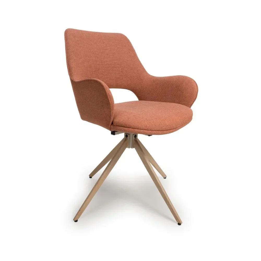 Modern dining chair with rust fabric upholstery and angled wooden legs, front angle view