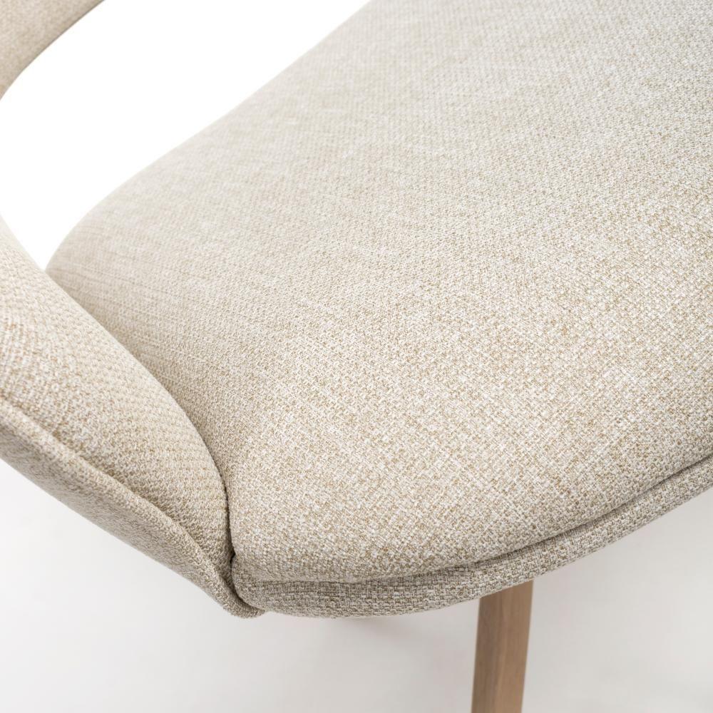 Closeup of beige fabric dining chair seat with curved backrest and wooden leg
