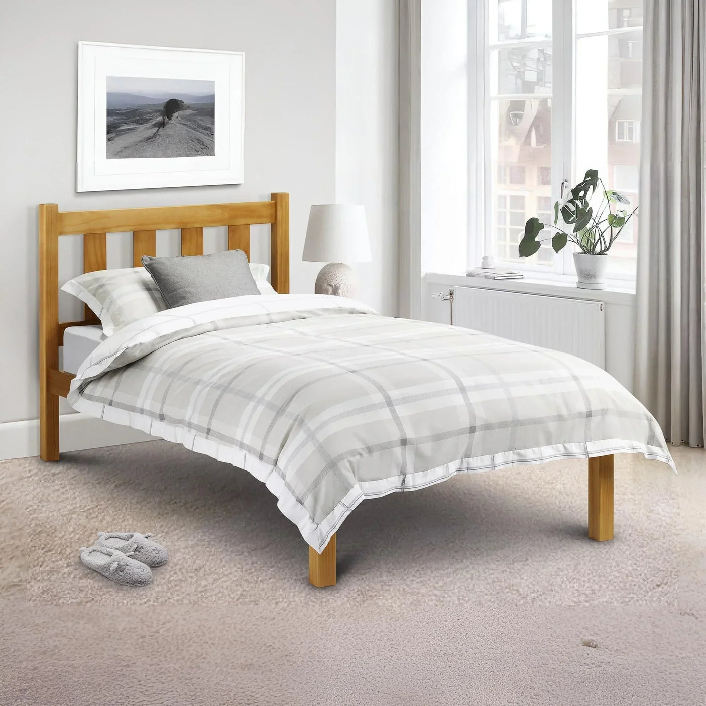 Wooden single bed frame with grey check bedding in bright bedroom