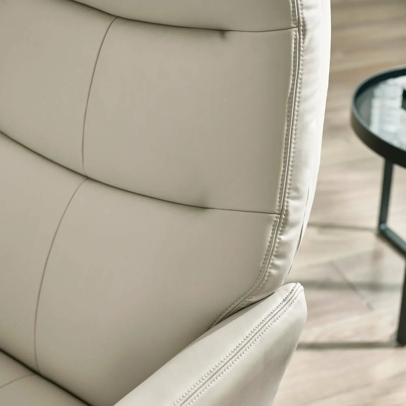 Grey accent chair close-up showing stitched leather upholstery and padded backrest