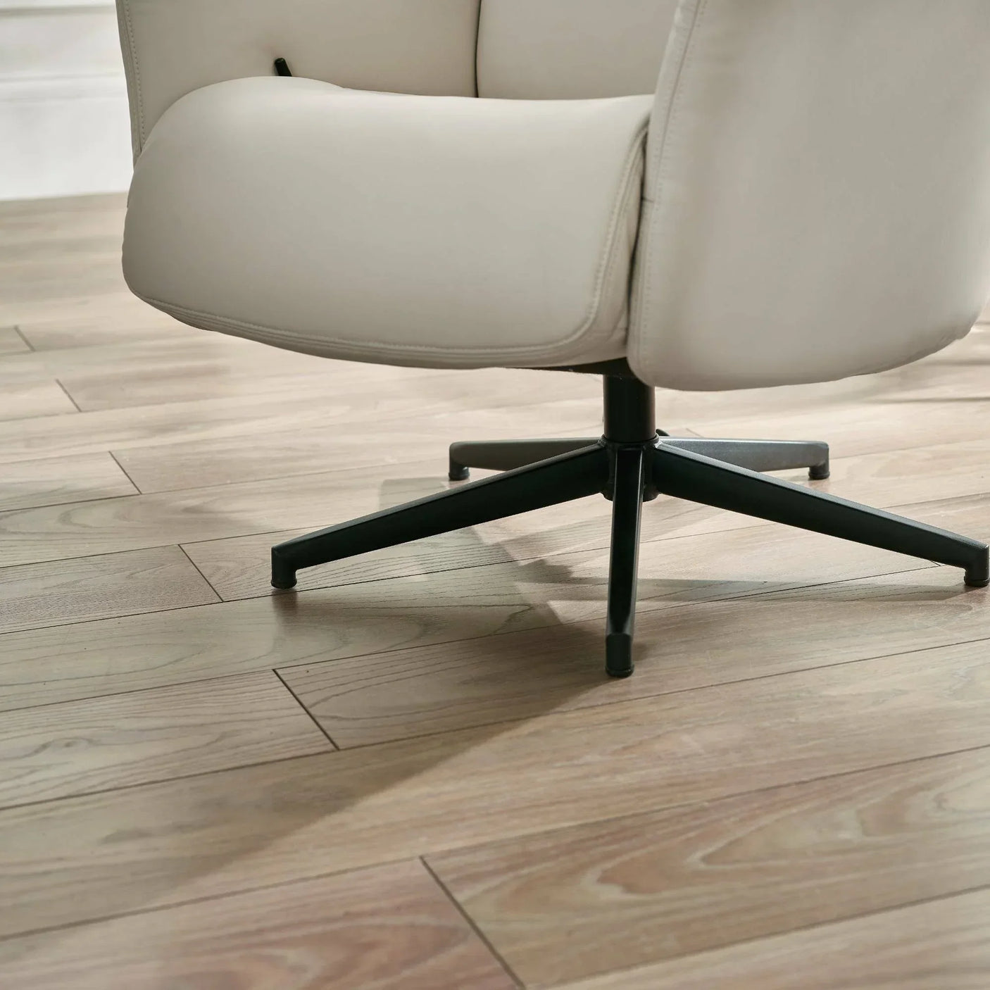 Grey accent chair with black swivel metal base on light wood flooring