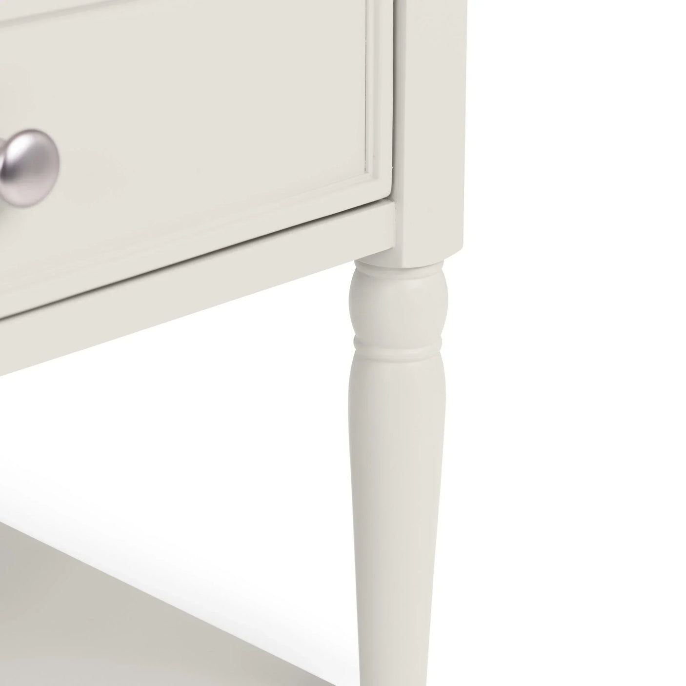 Close-up of white wooden table leg with drawer and round silver knob