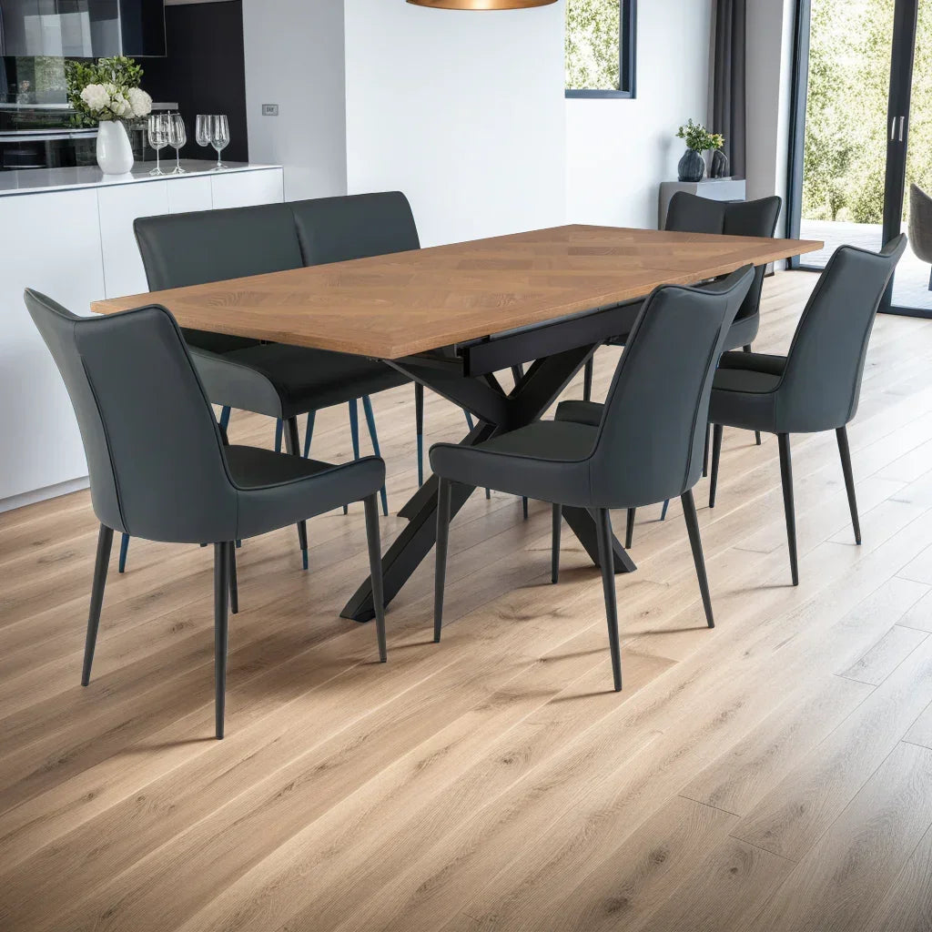 Rectangular wooden dining table with black metal legs and six grey leather chairs in modern kitchen
