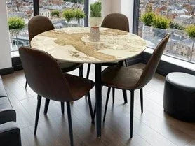 Round marble dining table with four brown chairs in modern apartment dining area