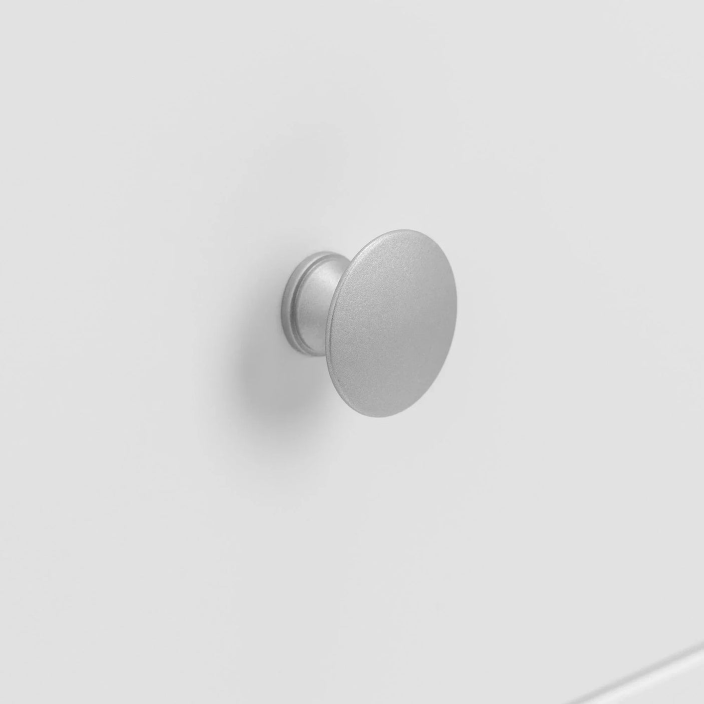 Round silver cabinet handle on white drawer front