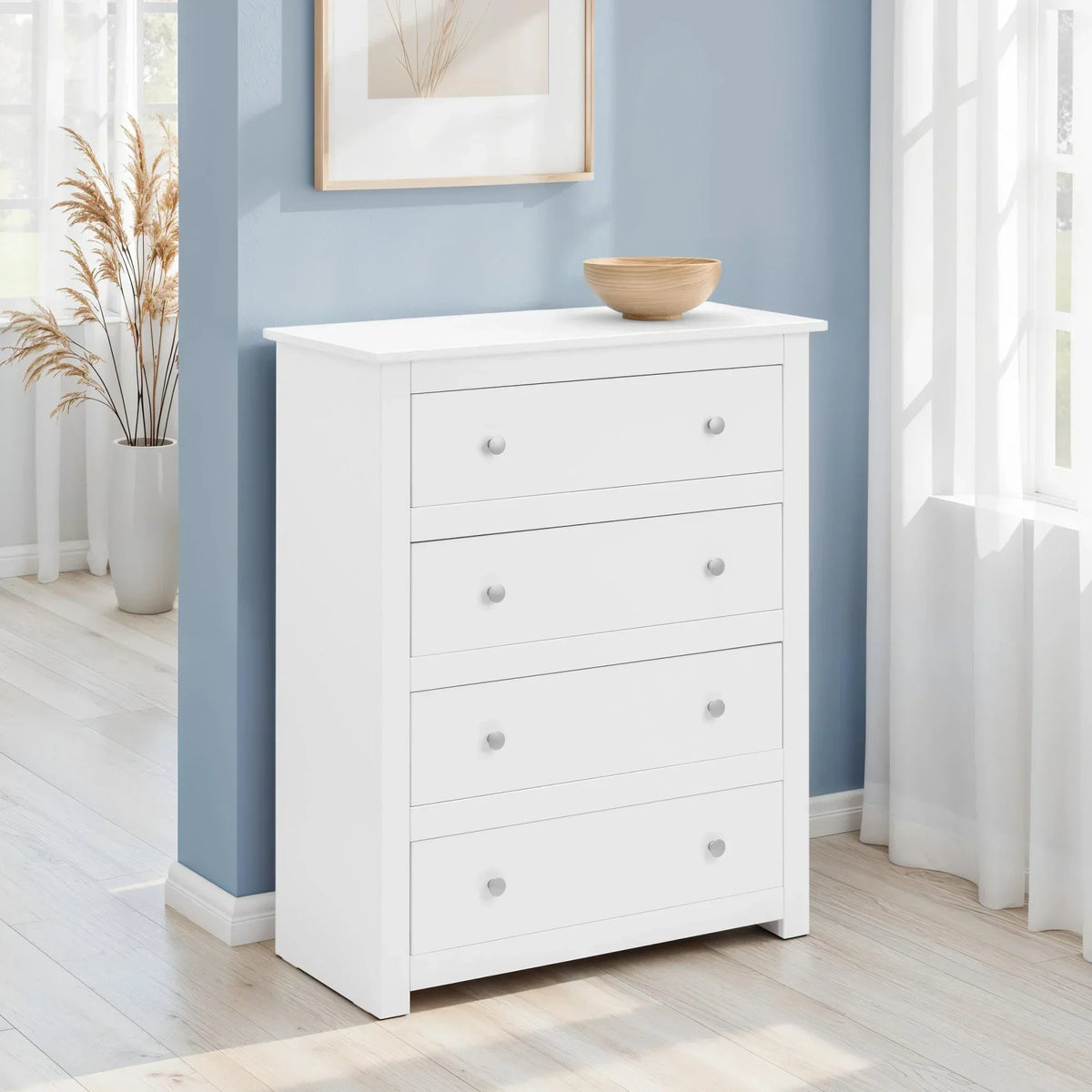 White chest of drawers with four handles in a bright bedroom by a blue wall
