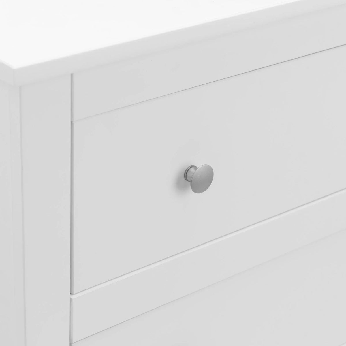 White chest of drawers with round silver handle, close up of top drawer corner