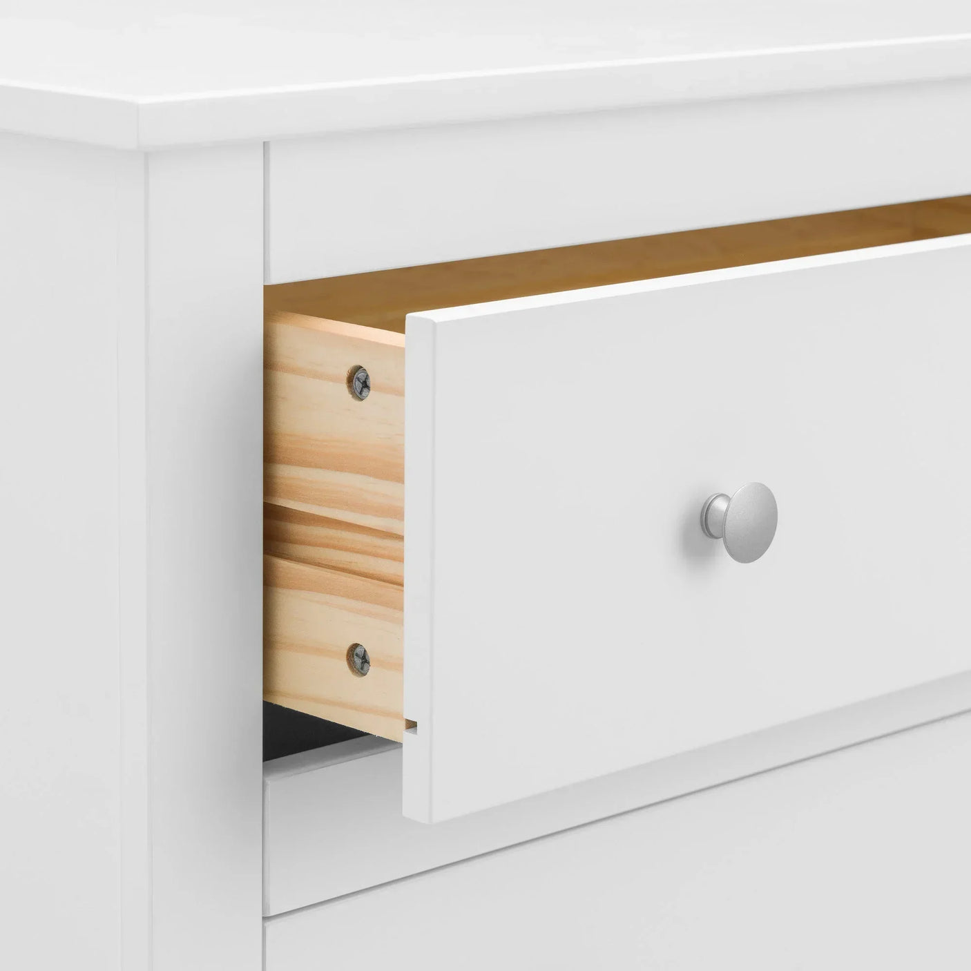 White chest of drawers close-up showing open drawer with silver knob