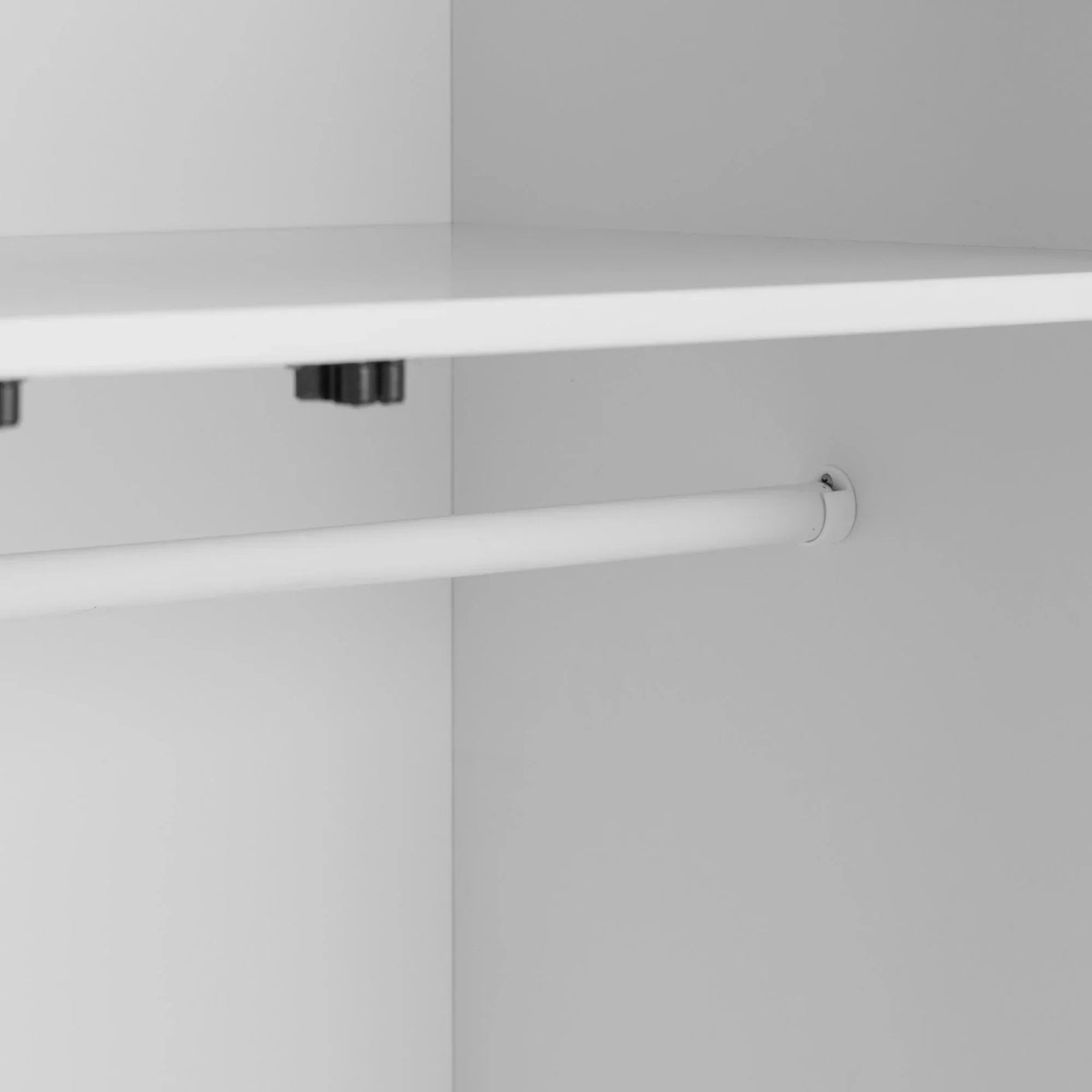 White wardrobe interior with hanging rail and upper shelf