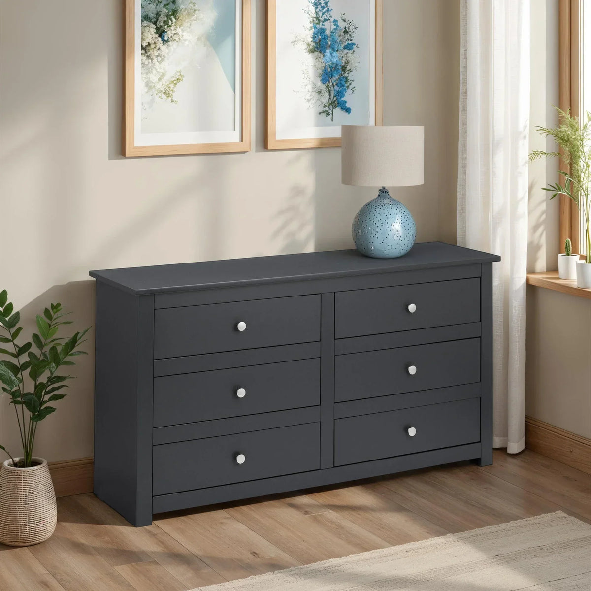 Dark grey six drawer chest with silver knobs in bright modern bedroom