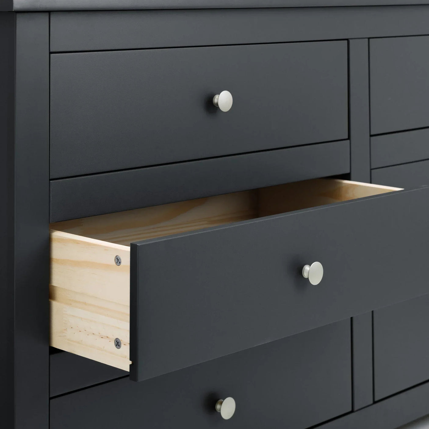 Matte black chest of drawers with brushed metal handles and one drawer open