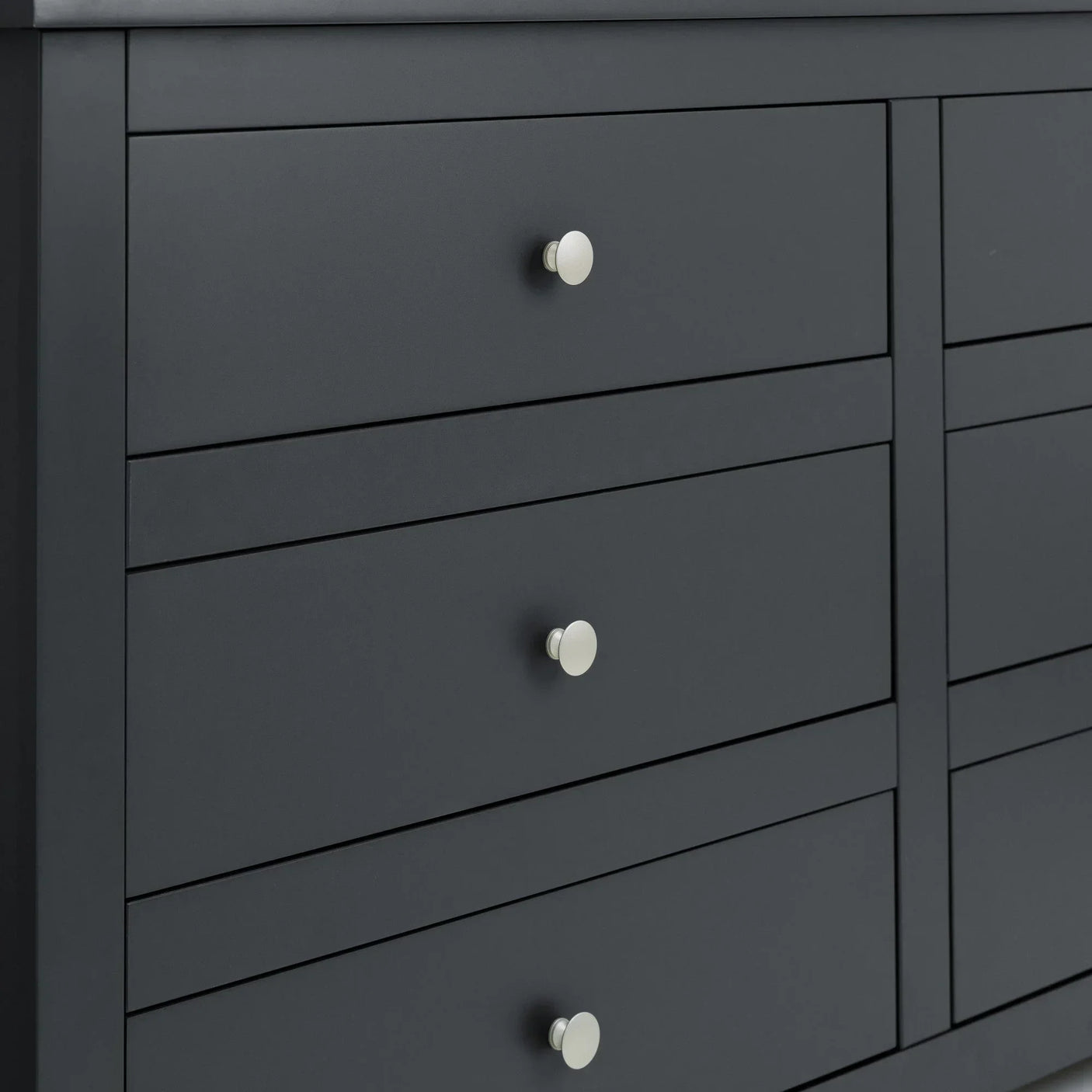 Matte black chest of drawers with round silver handles, close view of drawer fronts