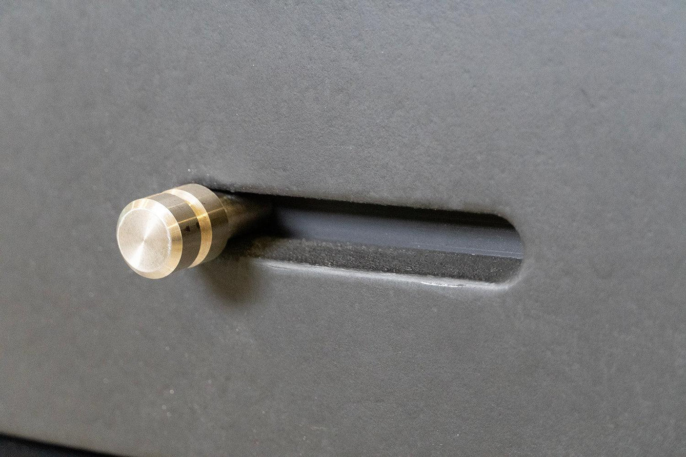 Brushed metal middle handle on grey wood furniture drawer close-up