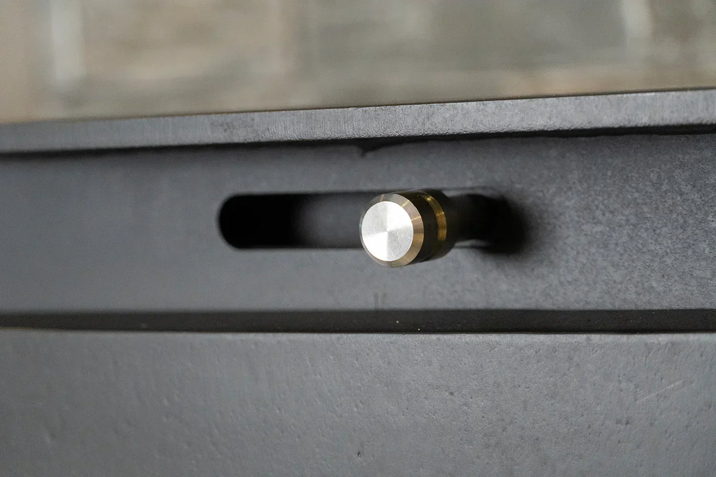 Metal handle detail on dark wood furniture piece with brushed steel finish