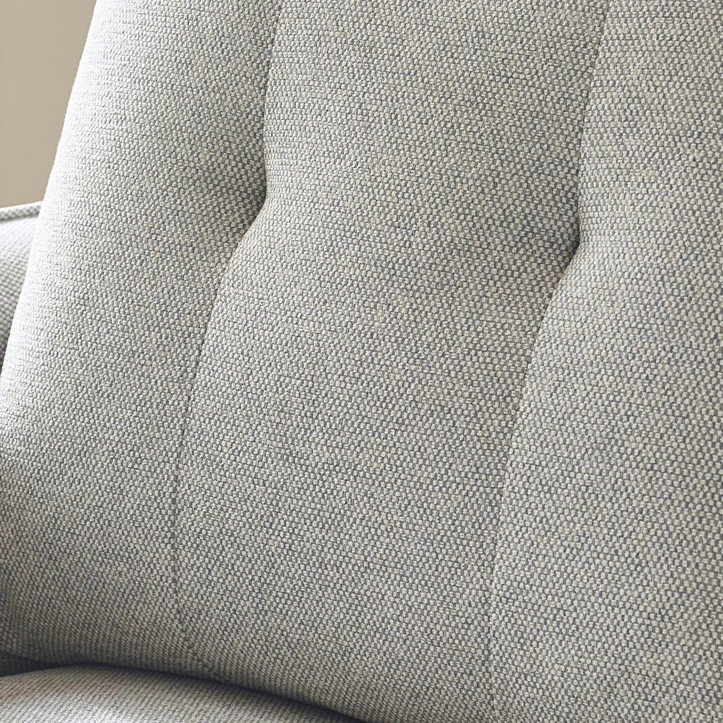 Light grey fabric sofa backrest with textured upholstery and button tufting detail