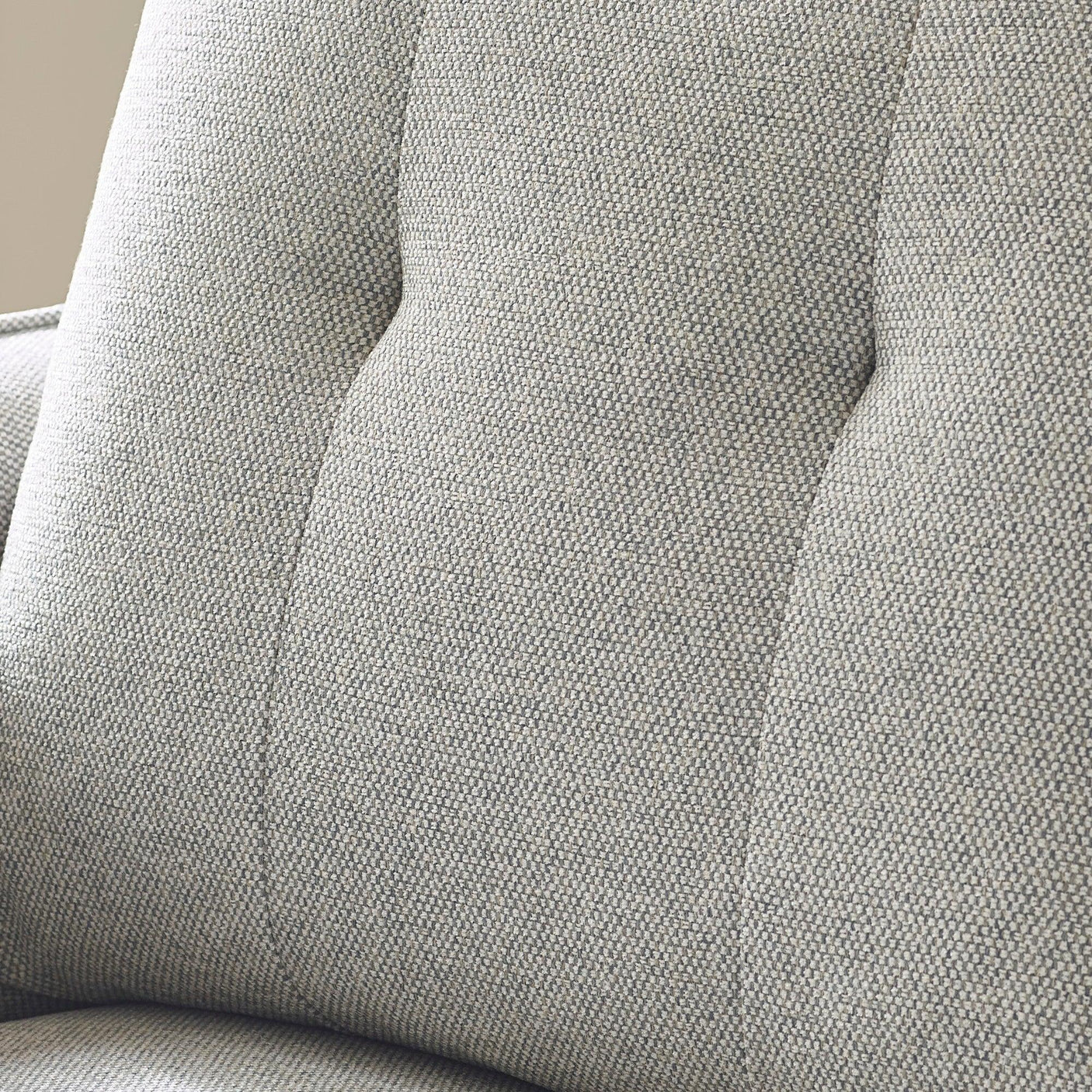 Closeup of grey fabric sofa backrest with tufted upholstery detail