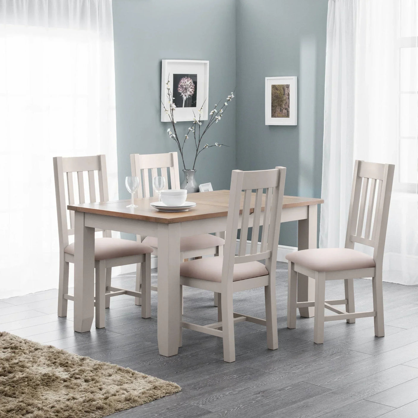 Four piece dining table set with light wood top and cream chairs in bright dining room