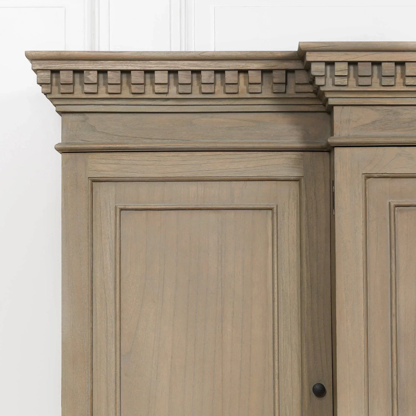 Detail of wooden cabinet top with decorative cornice and panelled wood door