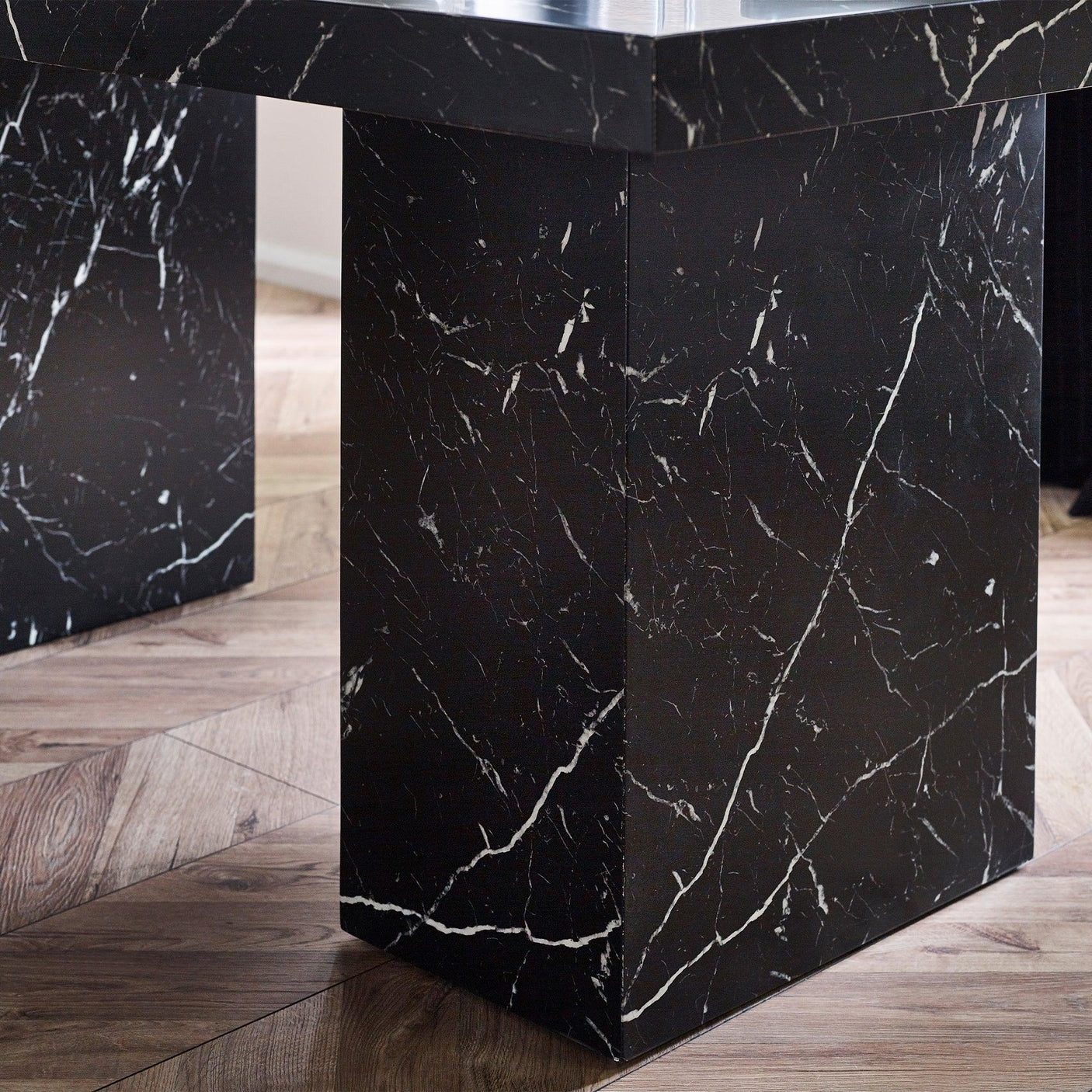 Black marble effect dining table base with white veining on wood floor