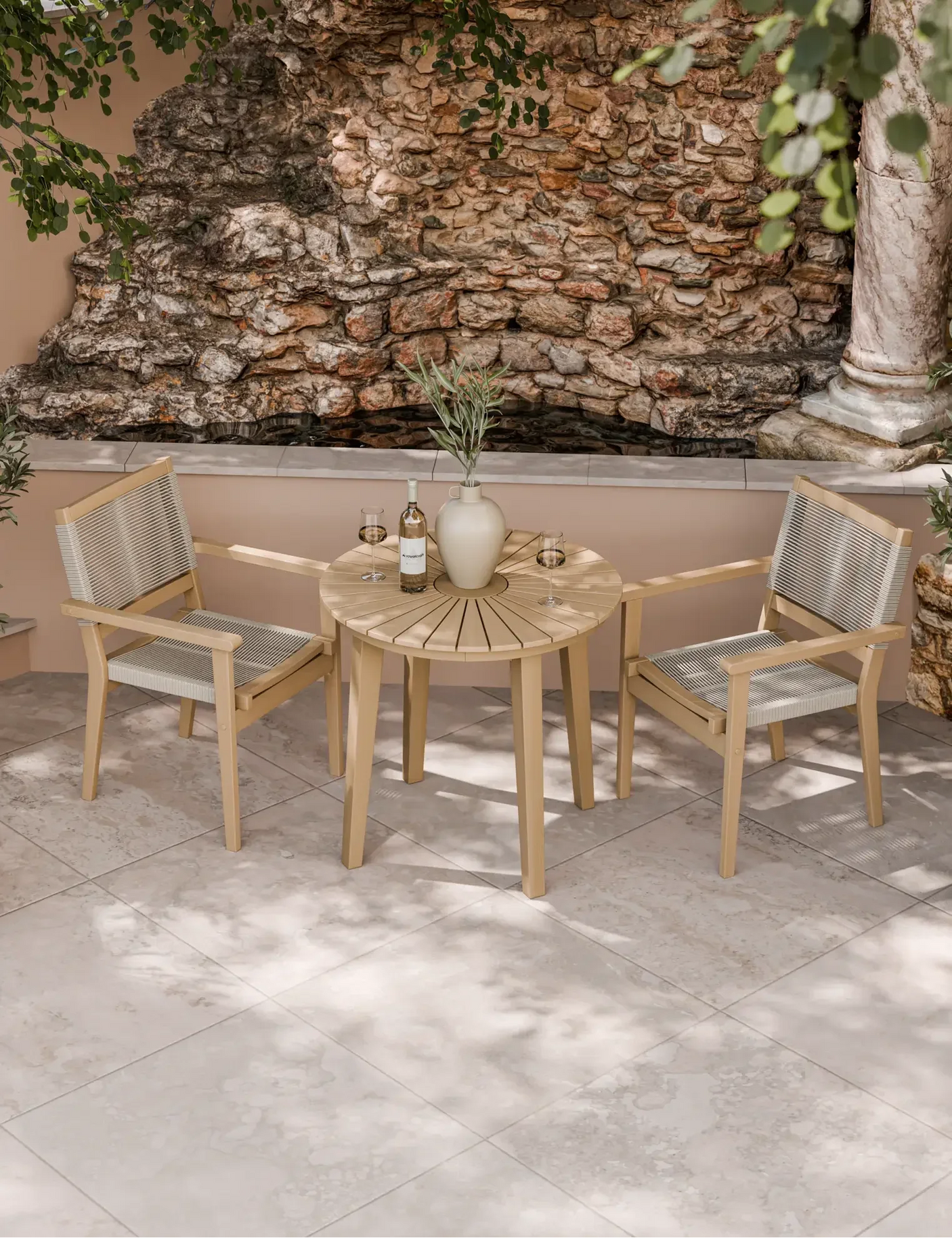 Outdoor bistro set with wooden table and two rope chairs on stone patio by a rock wall