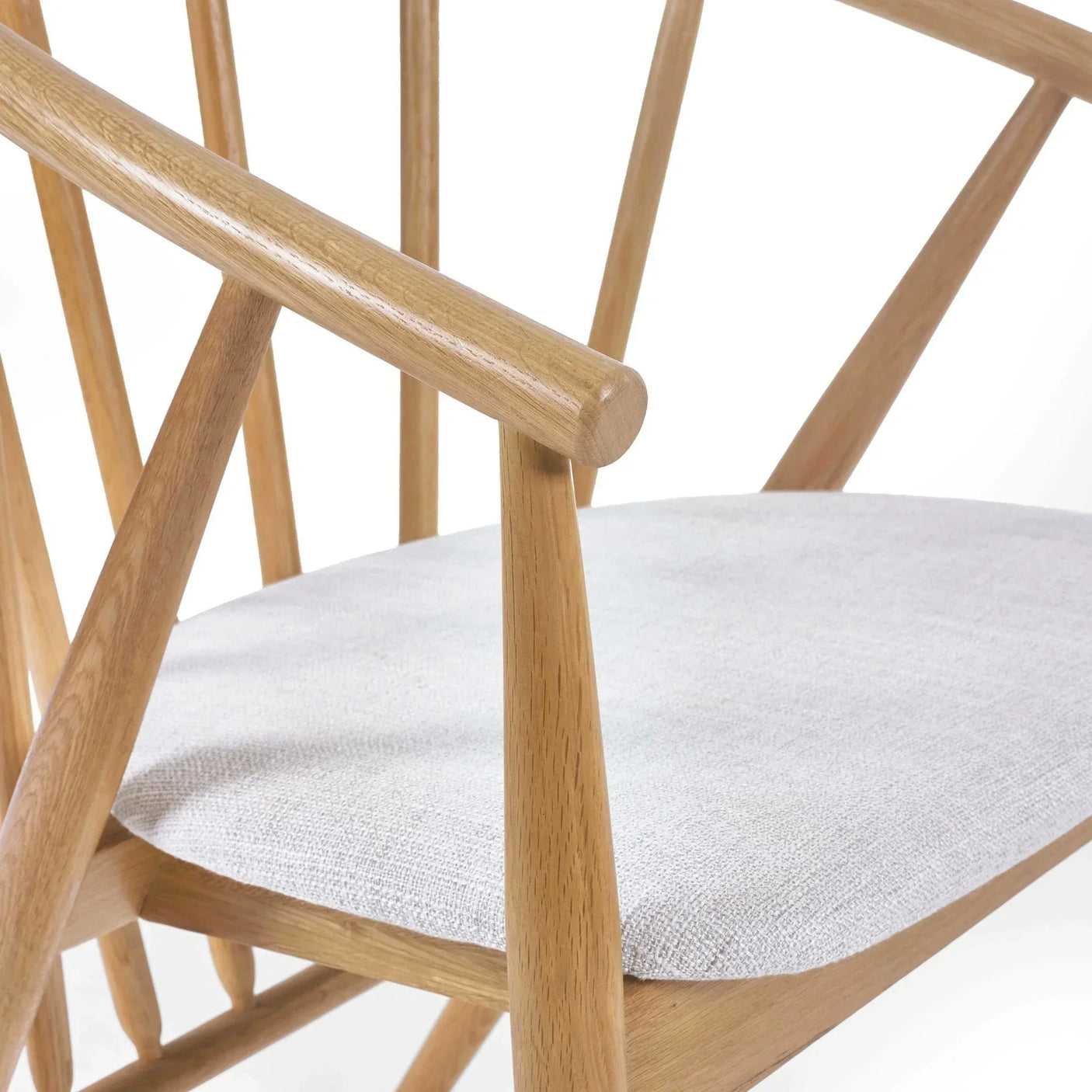Oak dining chair with light fabric seat, angled wooden arms and spindle backrest