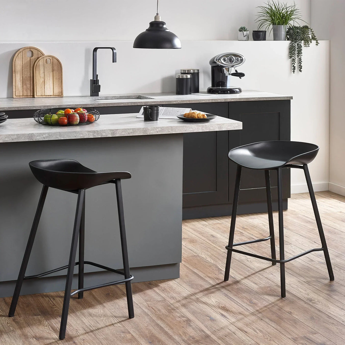 Black bar stools with curved seats and metal legs at modern kitchen breakfast bar