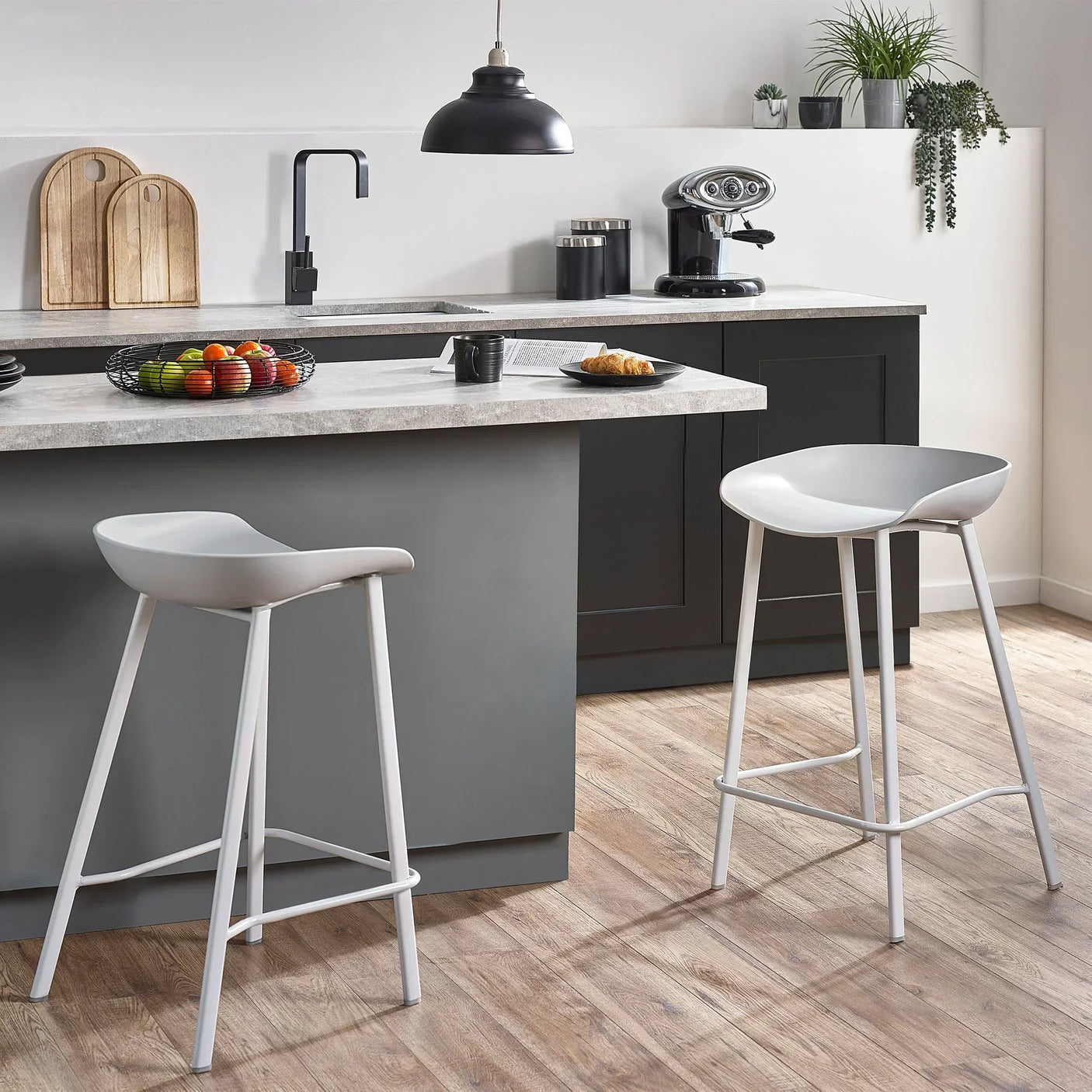 Grey bar stools with curved seats at modern kitchen island with wood flooring