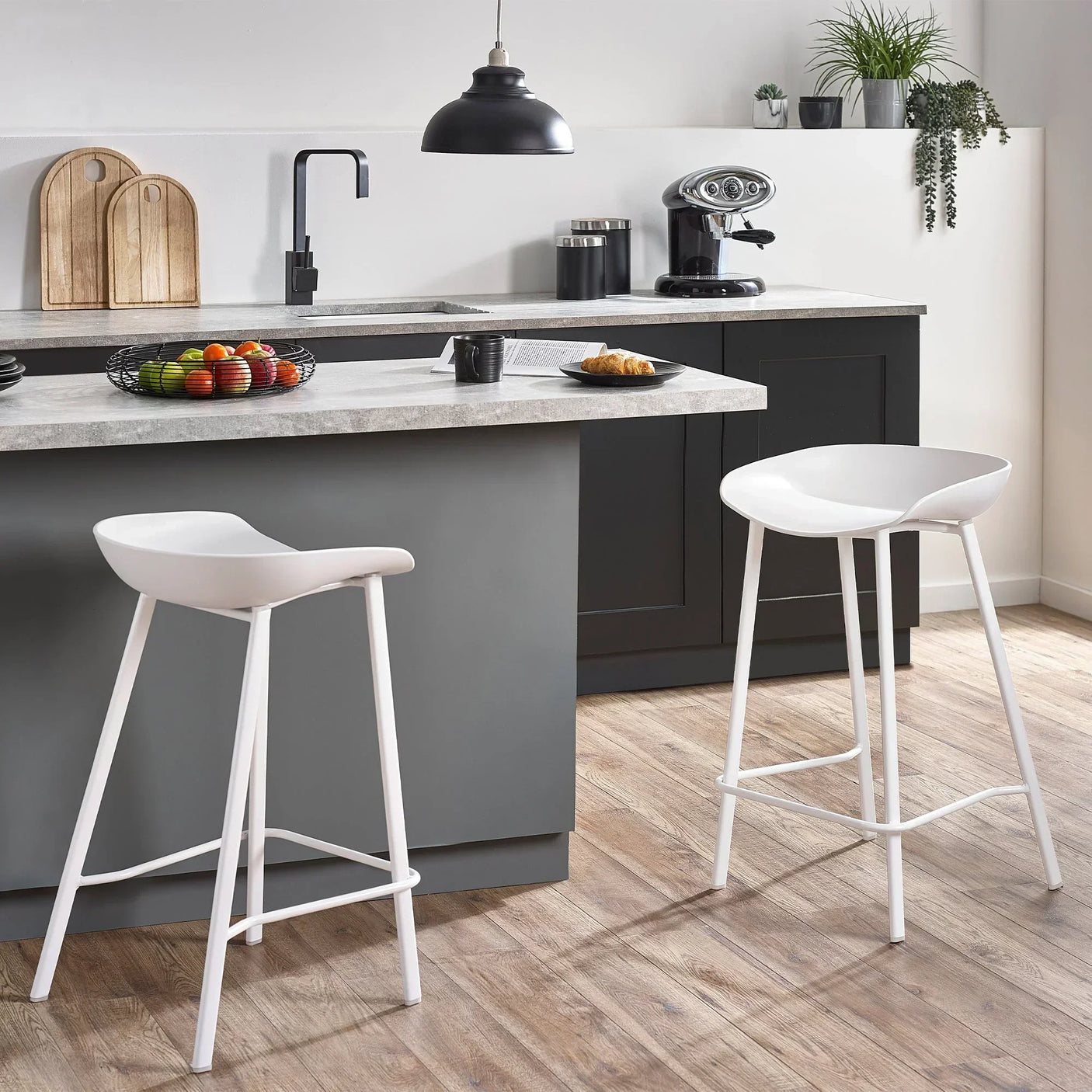 White bar stools with curved seats at a modern kitchen island with grey cabinets