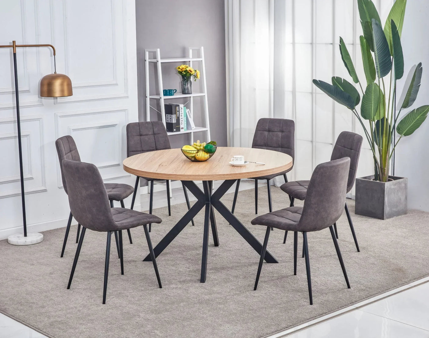 Round oak dining table with black legs and six grey fabric chairs in modern dining room