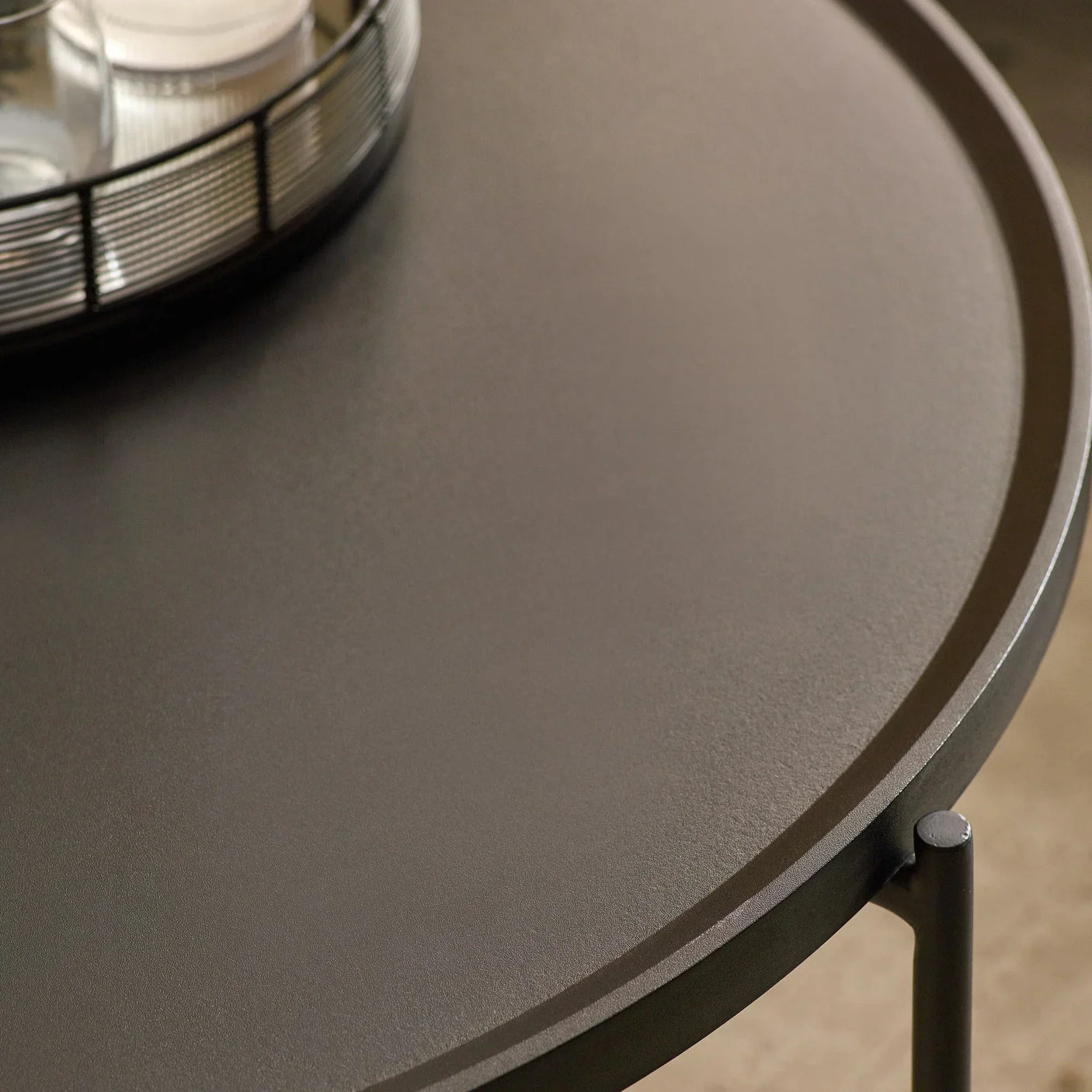 Round metal side table with raised edge and black tray detail