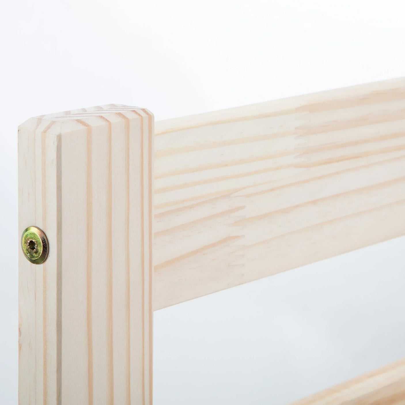 Closeup of light wood bed frame corner with visible grain and metal screw