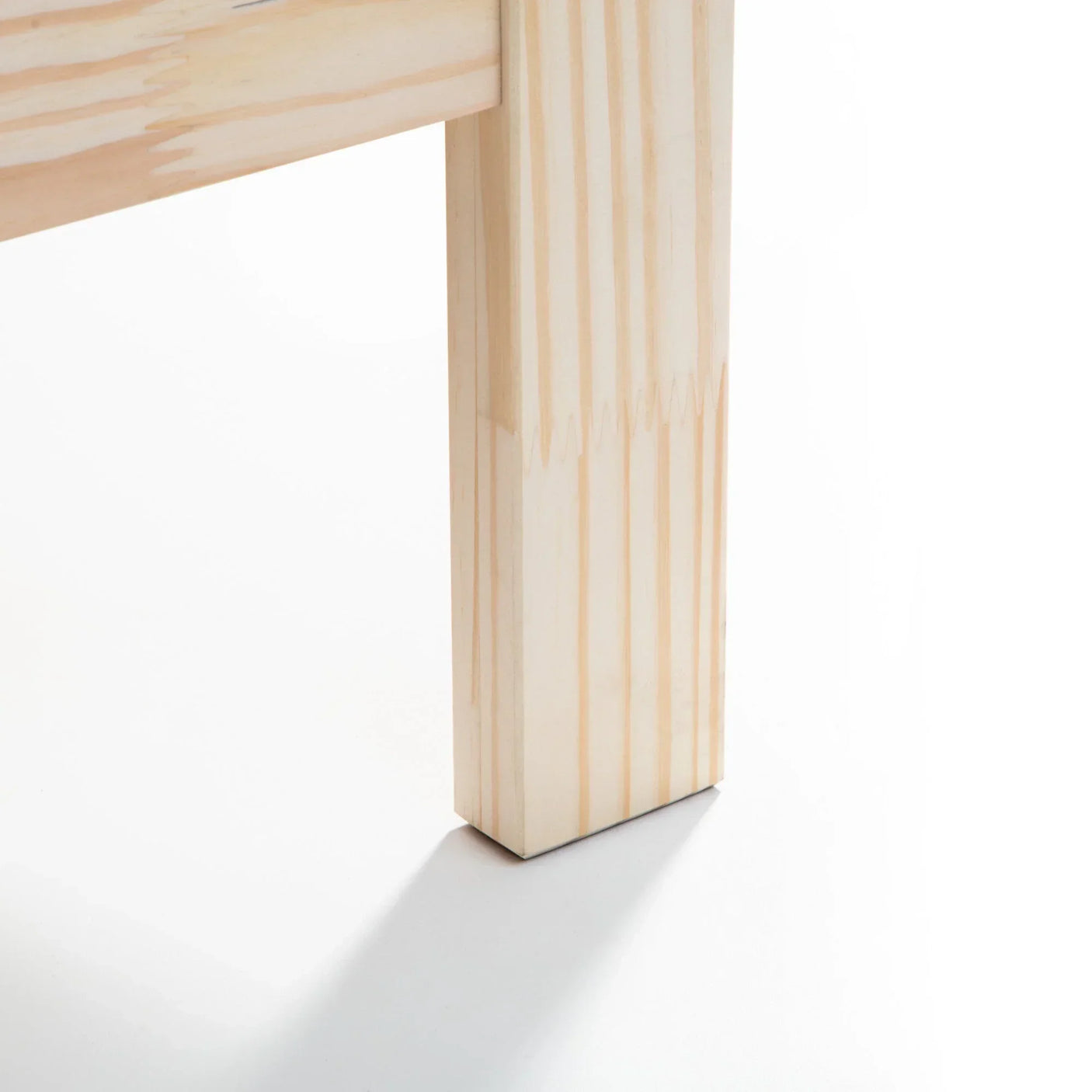 Closeup of light pine wooden bed frame leg on white background