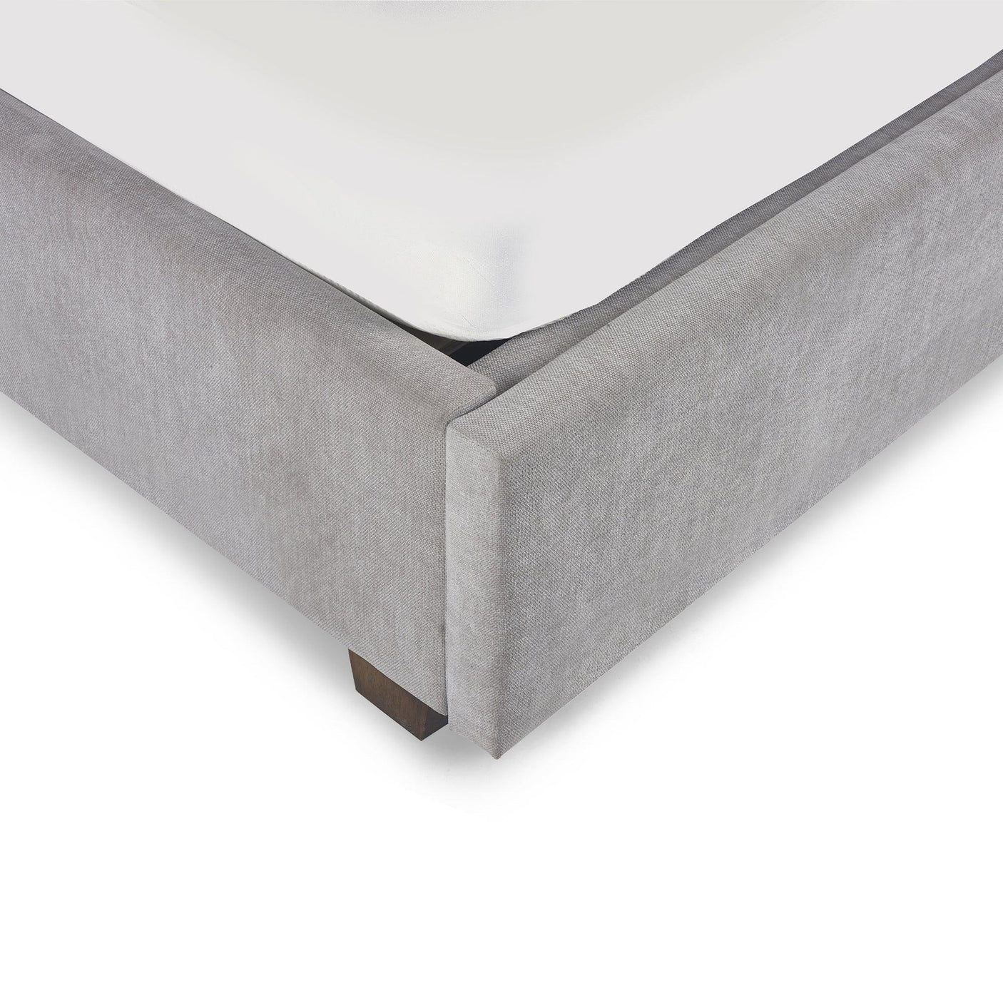 Close up of upholstered bed frame corner in light grey fabric with wooden leg
