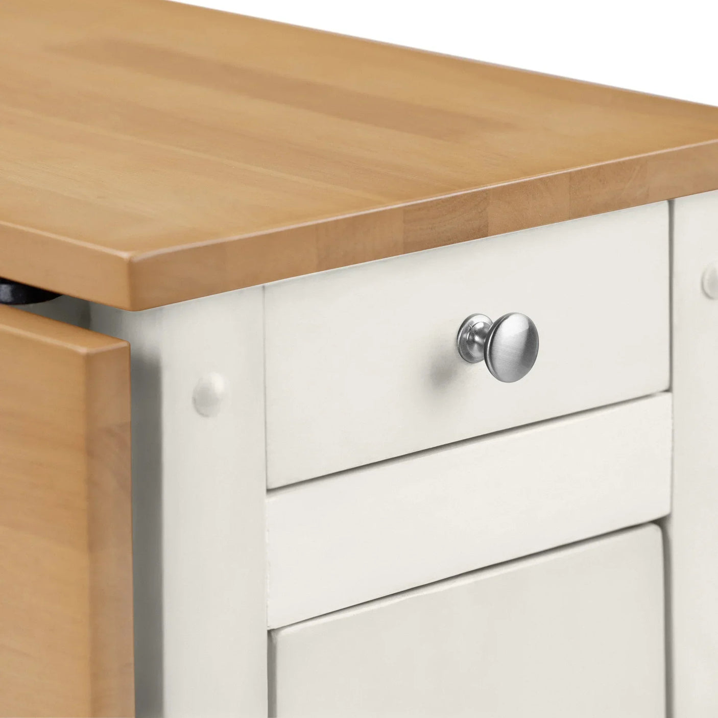 Closeup of kitchen cabinet with light wood top, white drawer, and silver knob handle