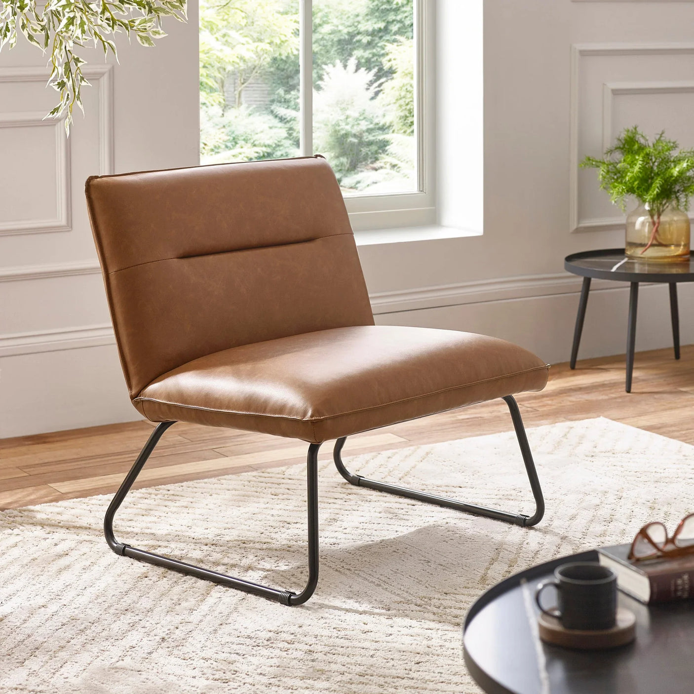 Brown leather accent chair with black metal legs on cream rug in modern living room