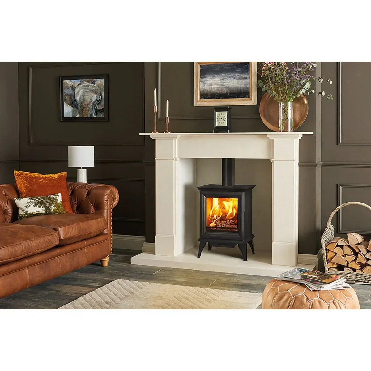 Electric stove fireplace with cream surround in stylish living room, brown sofa, log basket nearby