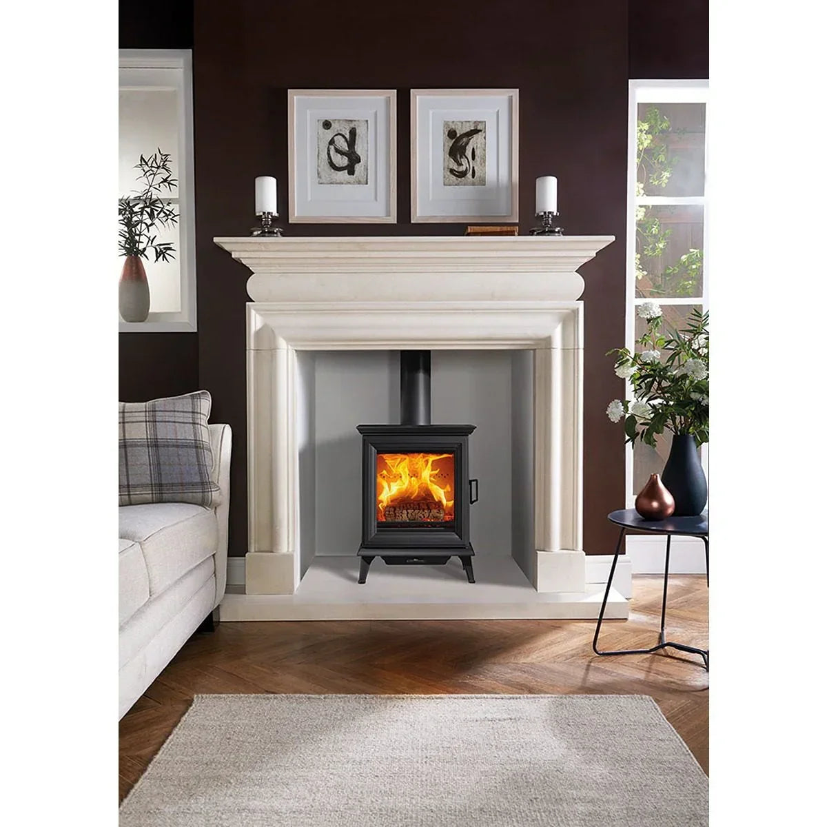 Black wood burning stove in cream fireplace with fire, modern living room setting