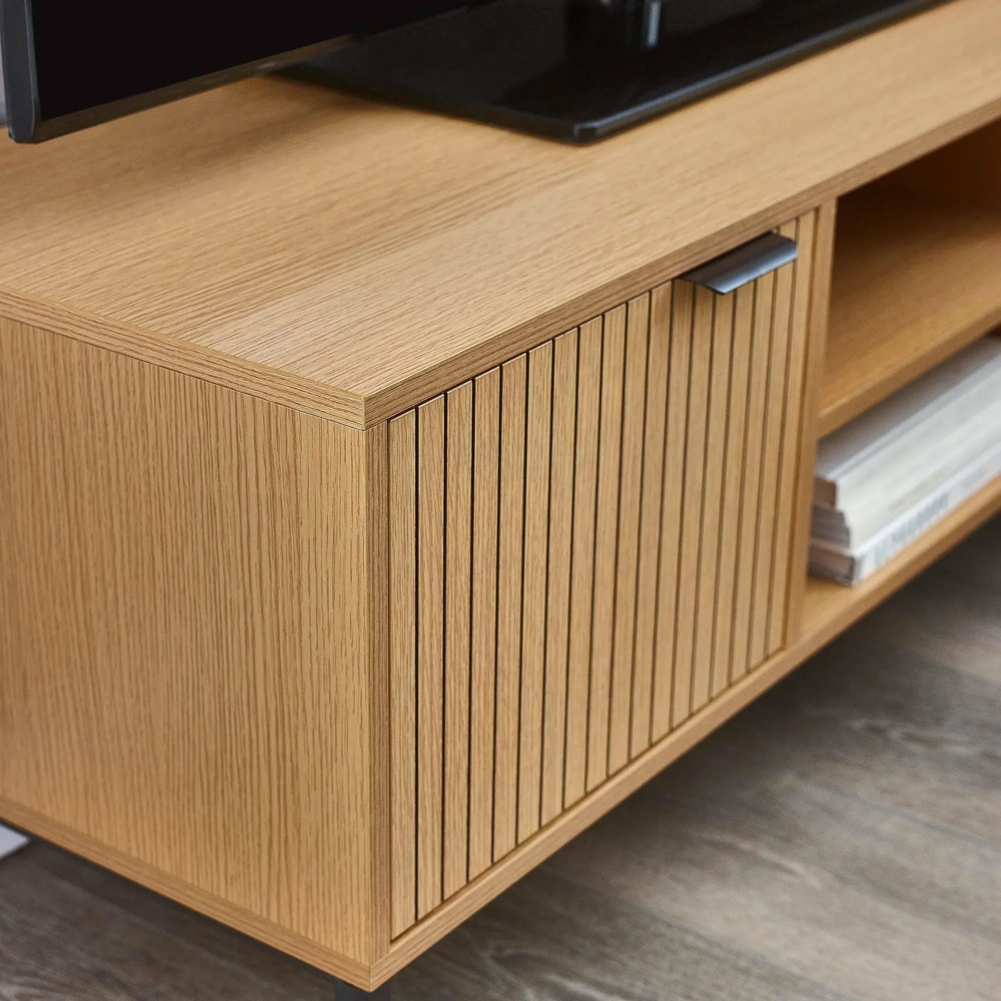Oak TV unit with slatted cabinet door and open shelving on wood flooring