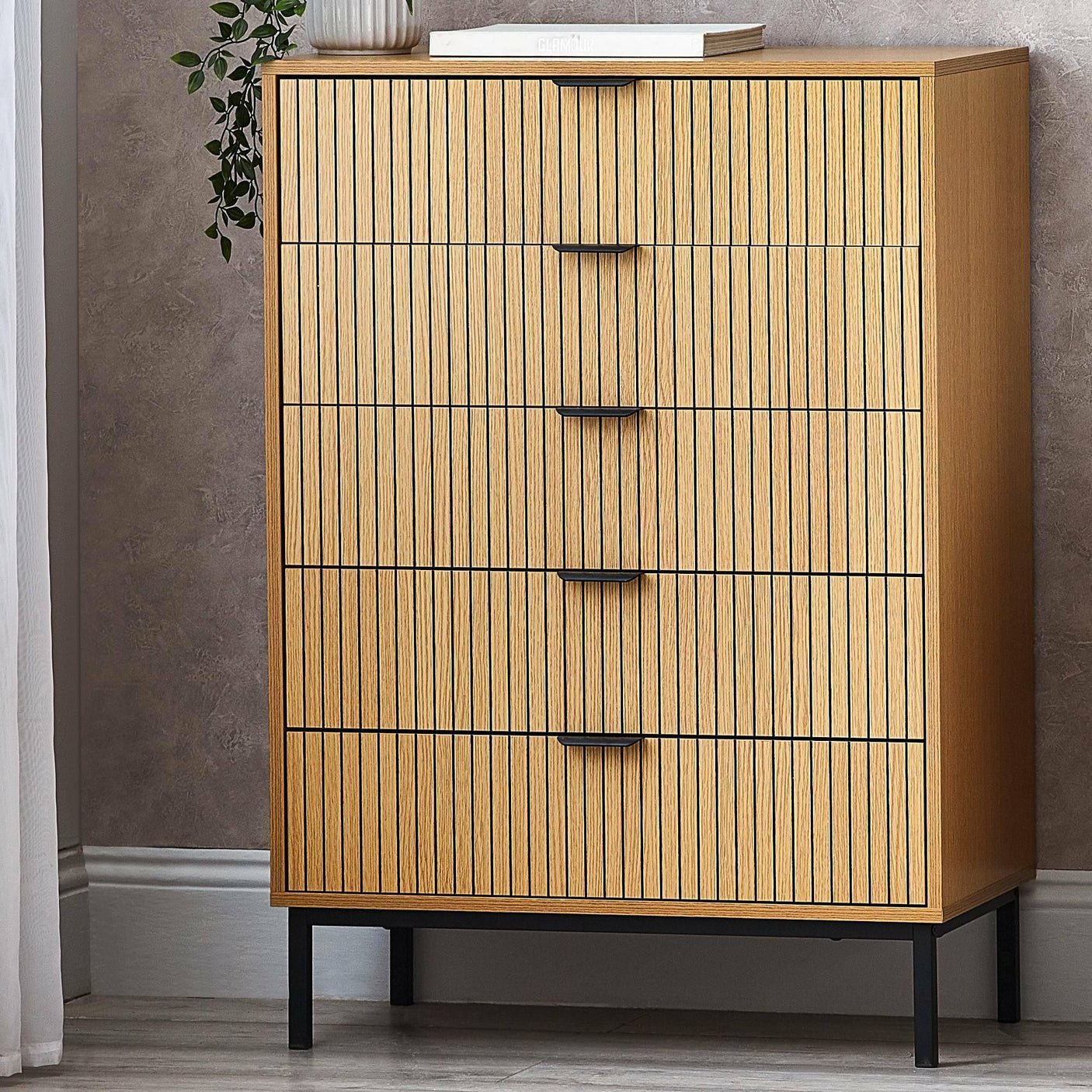 Sia 5 drawer chest with vertical wood slats and black legs against a textured wall