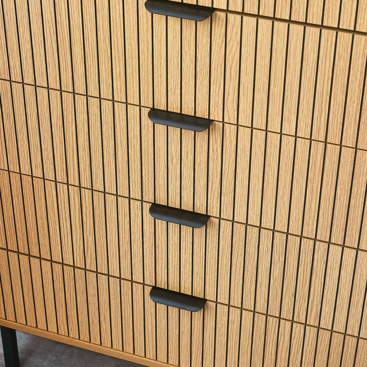 Wooden chest of drawers with vertical slatted design and black handles close up