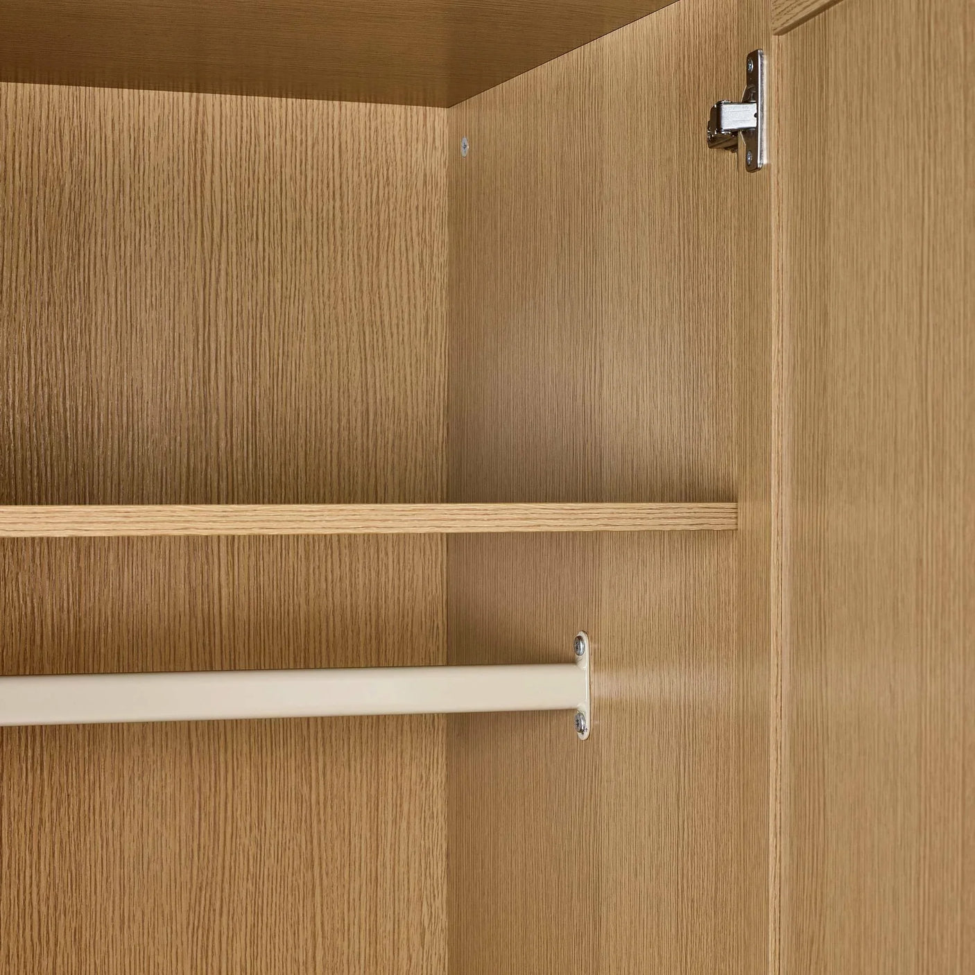 Oak wardrobe interior with hanging rail and shelf, close-up of wood grain and fittings