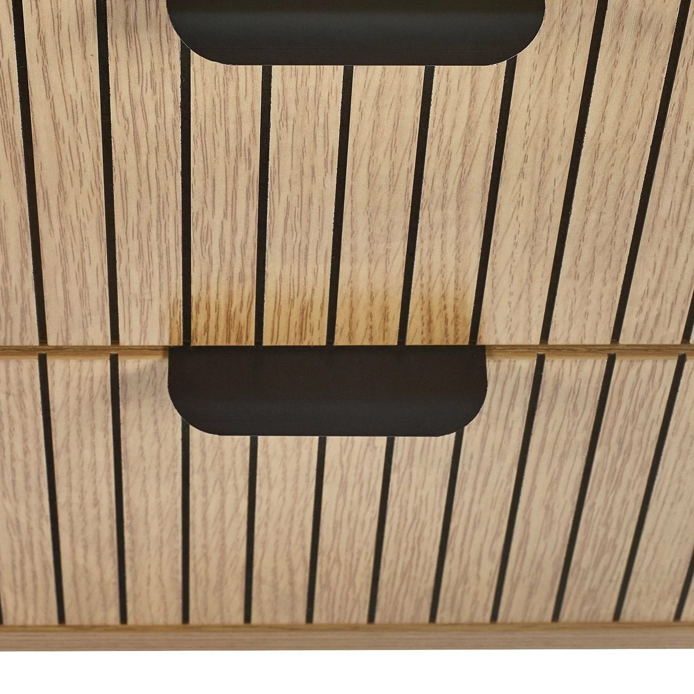 Closeup of wood chest of drawers with vertical black lines and recessed black handles