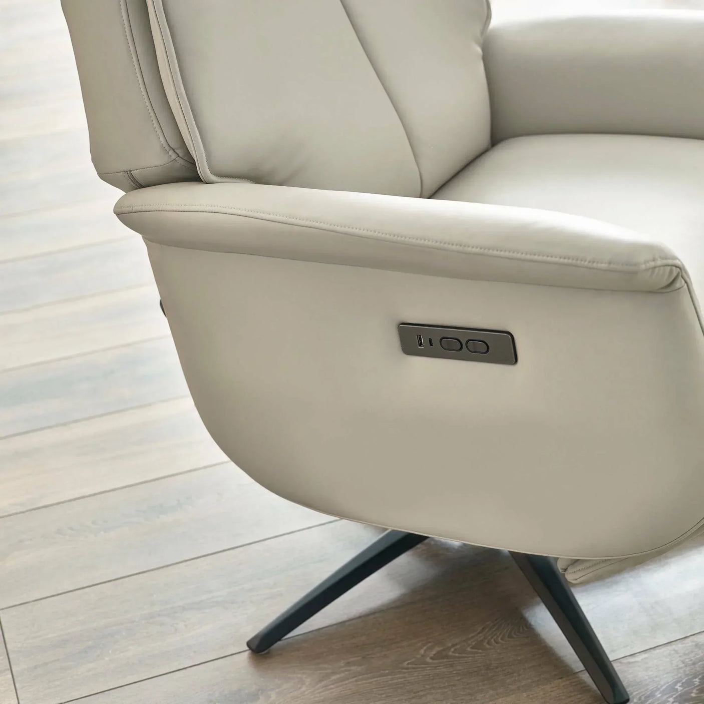Beige dual recliner chair with side control panel on wooden floor
