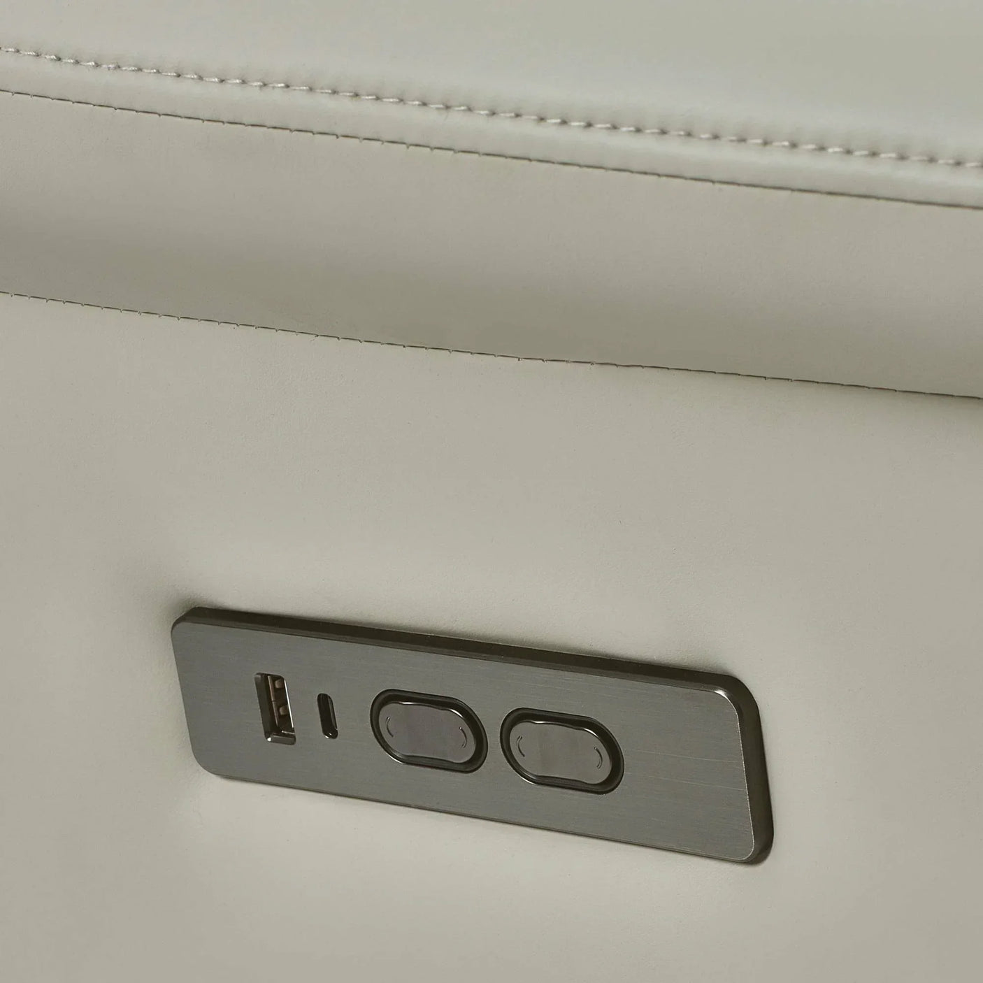 Close-up of recliner sofa arm with USB port and control buttons in light leather