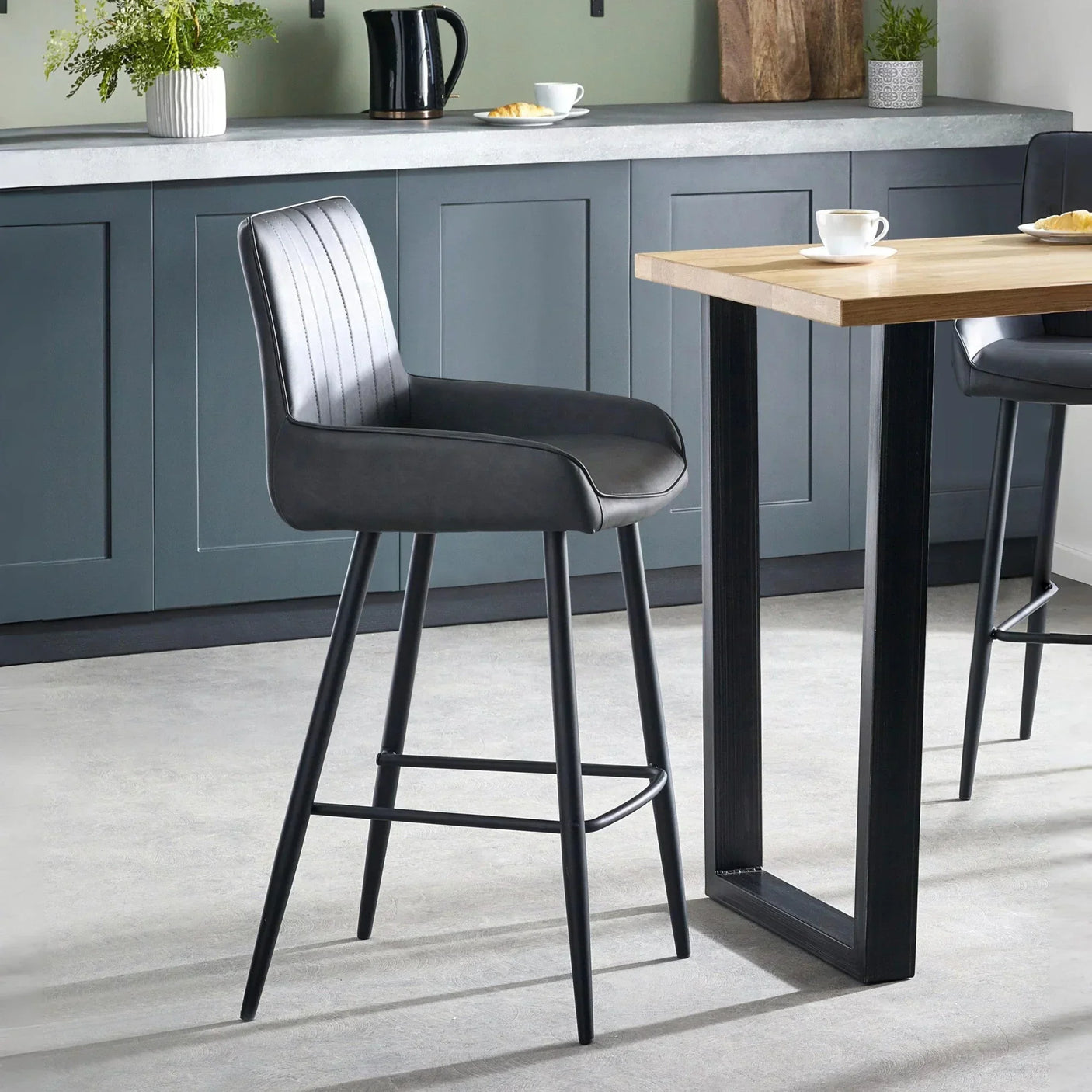 Black faux leather bar stool with backrest and metal legs in modern kitchen setting