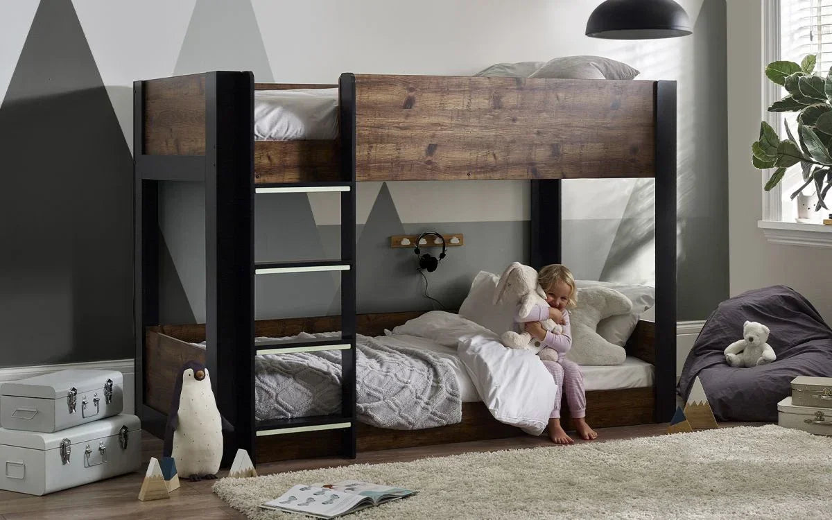 Wooden bunk bed with black frame in kids bedroom, child sitting on lower bed