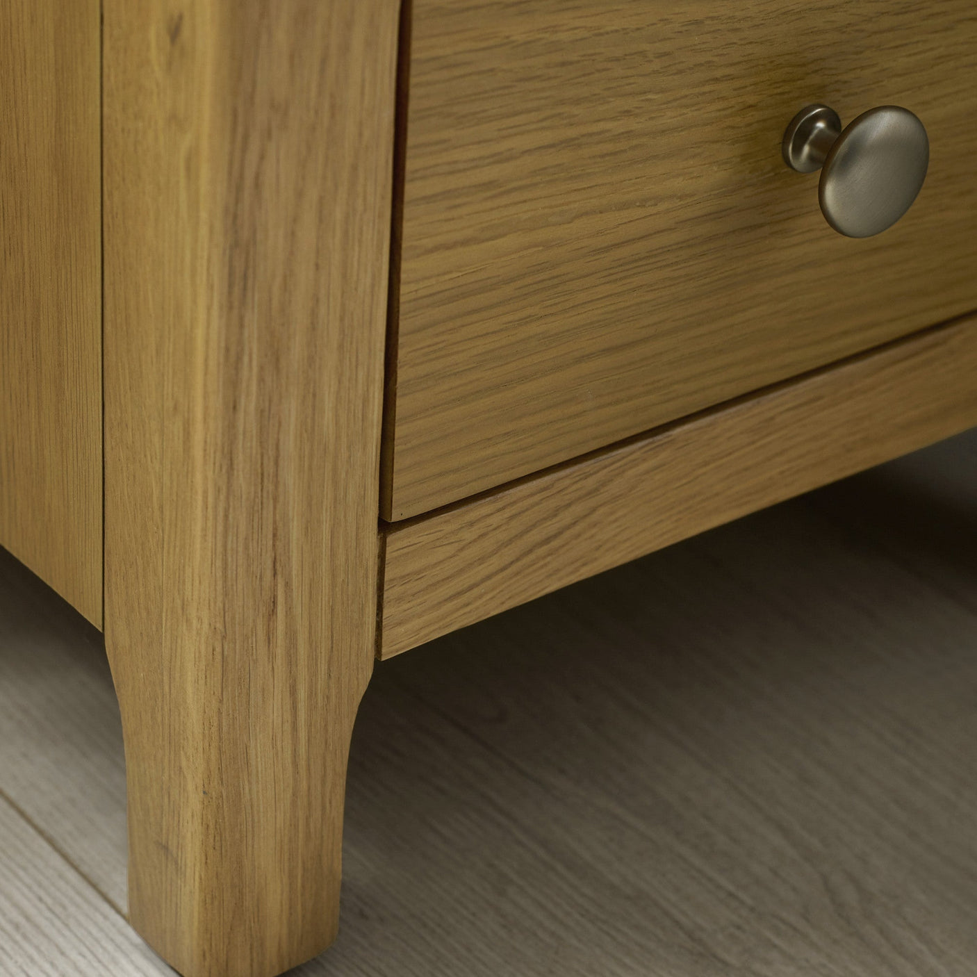 Close-up of the corner and top surface of the light oak bedside table showing wood texture