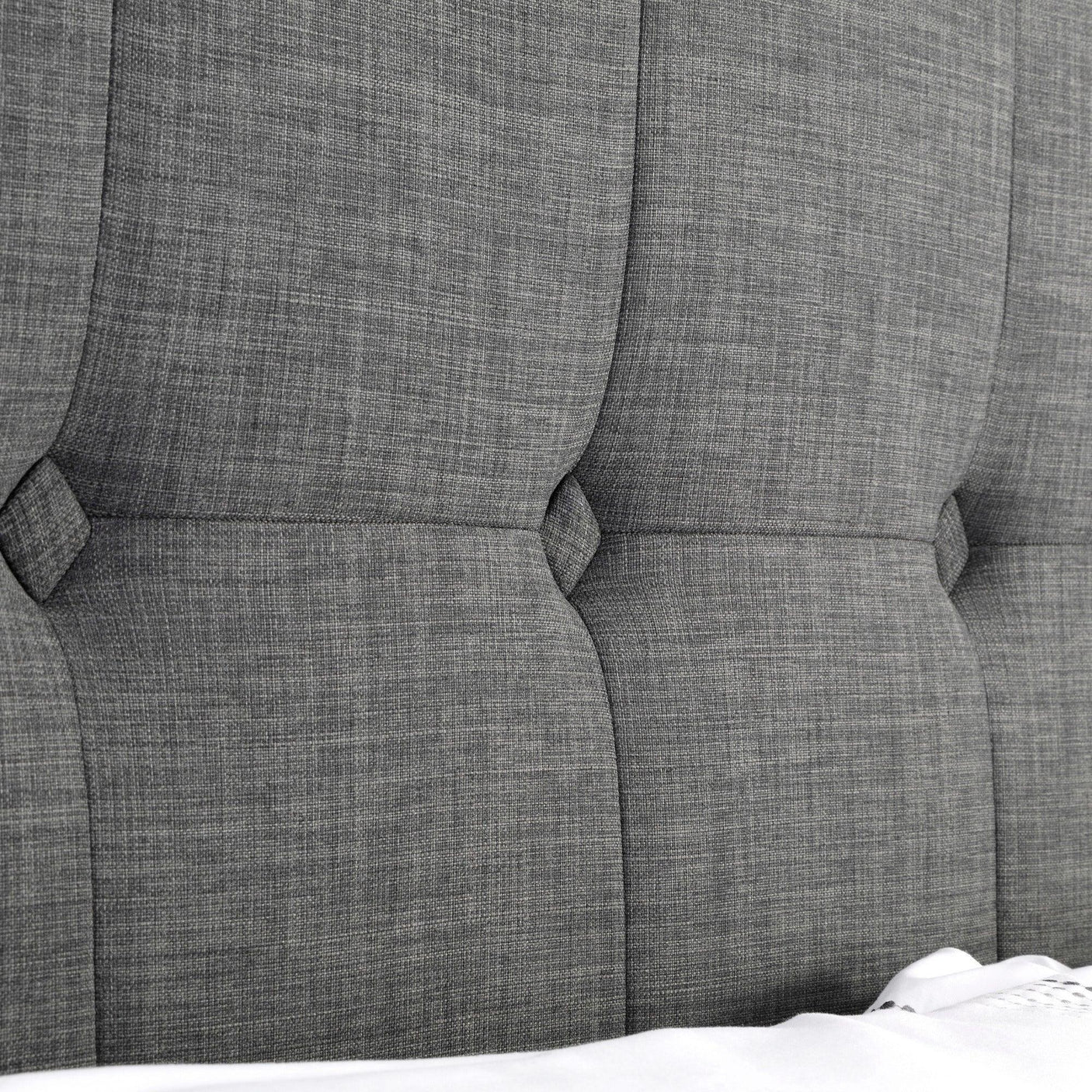 Detail of slate linen king bed headboard with tufted upholstery